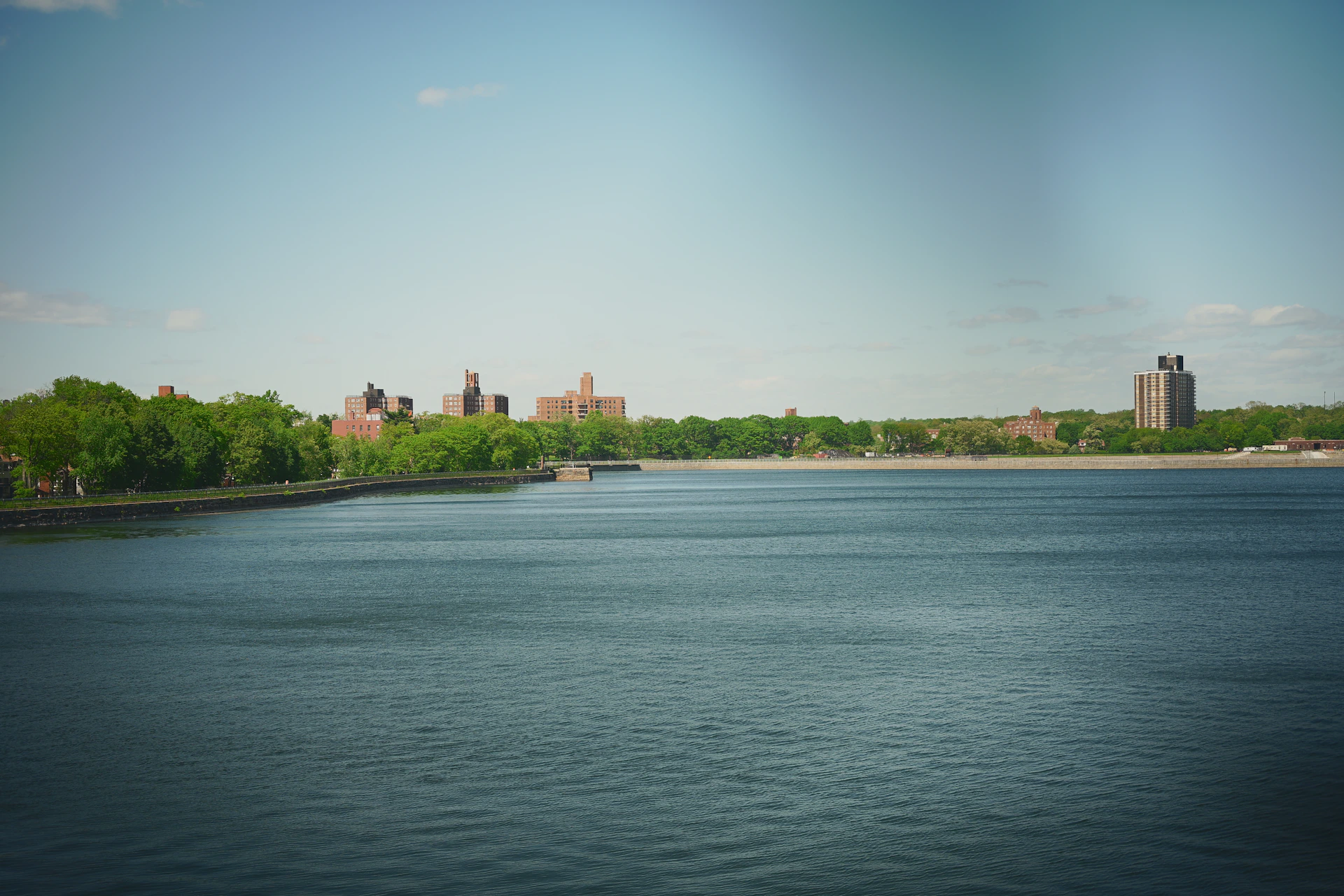 City skyline visible across a large reservoir with green trees.