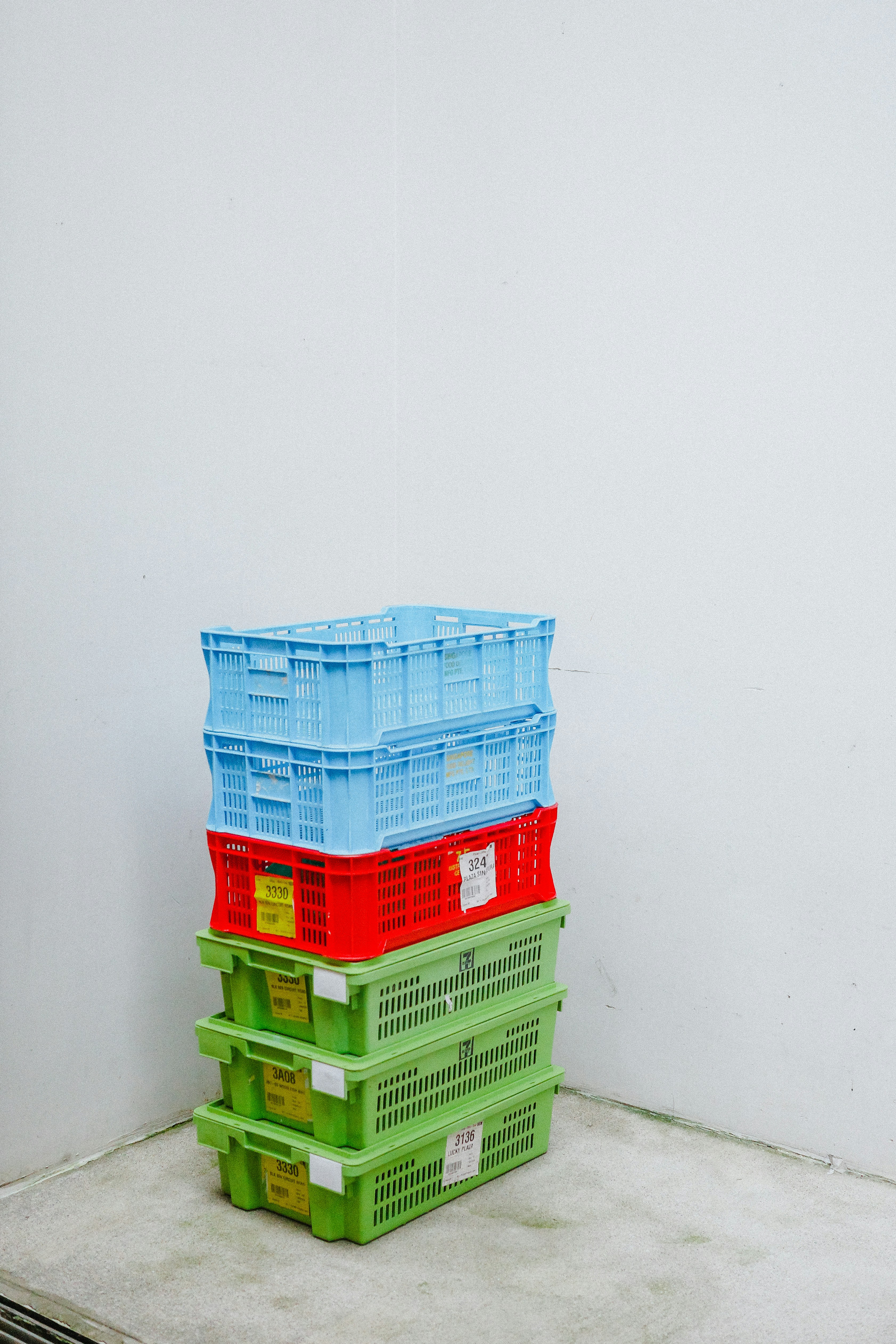 A stack of colorful plastic crates against a white wall.