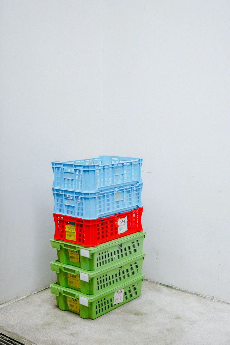 Stack of colourful plastic crates against a white wall