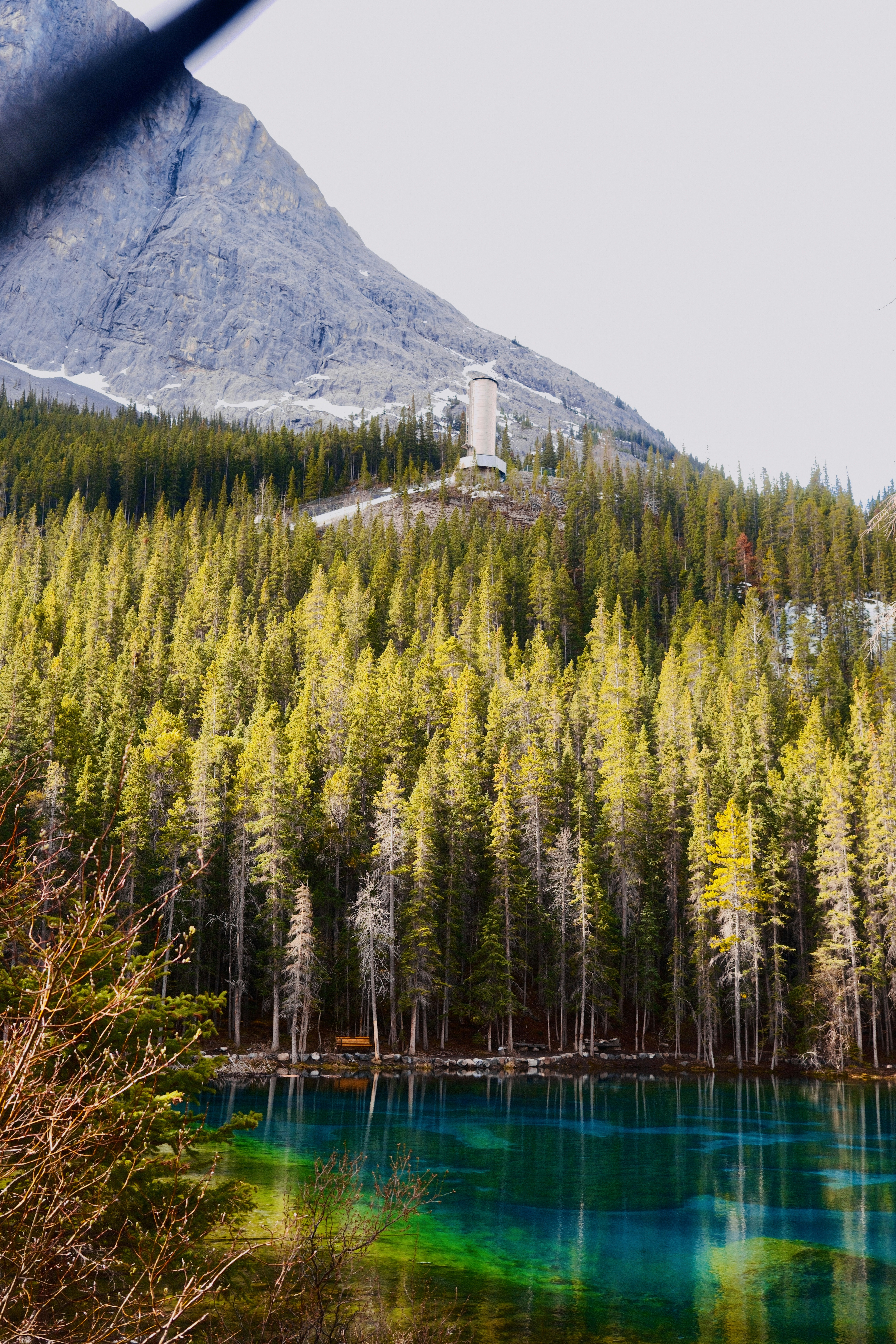 Vibrant turquoise lake bordered by a forest and mountain.