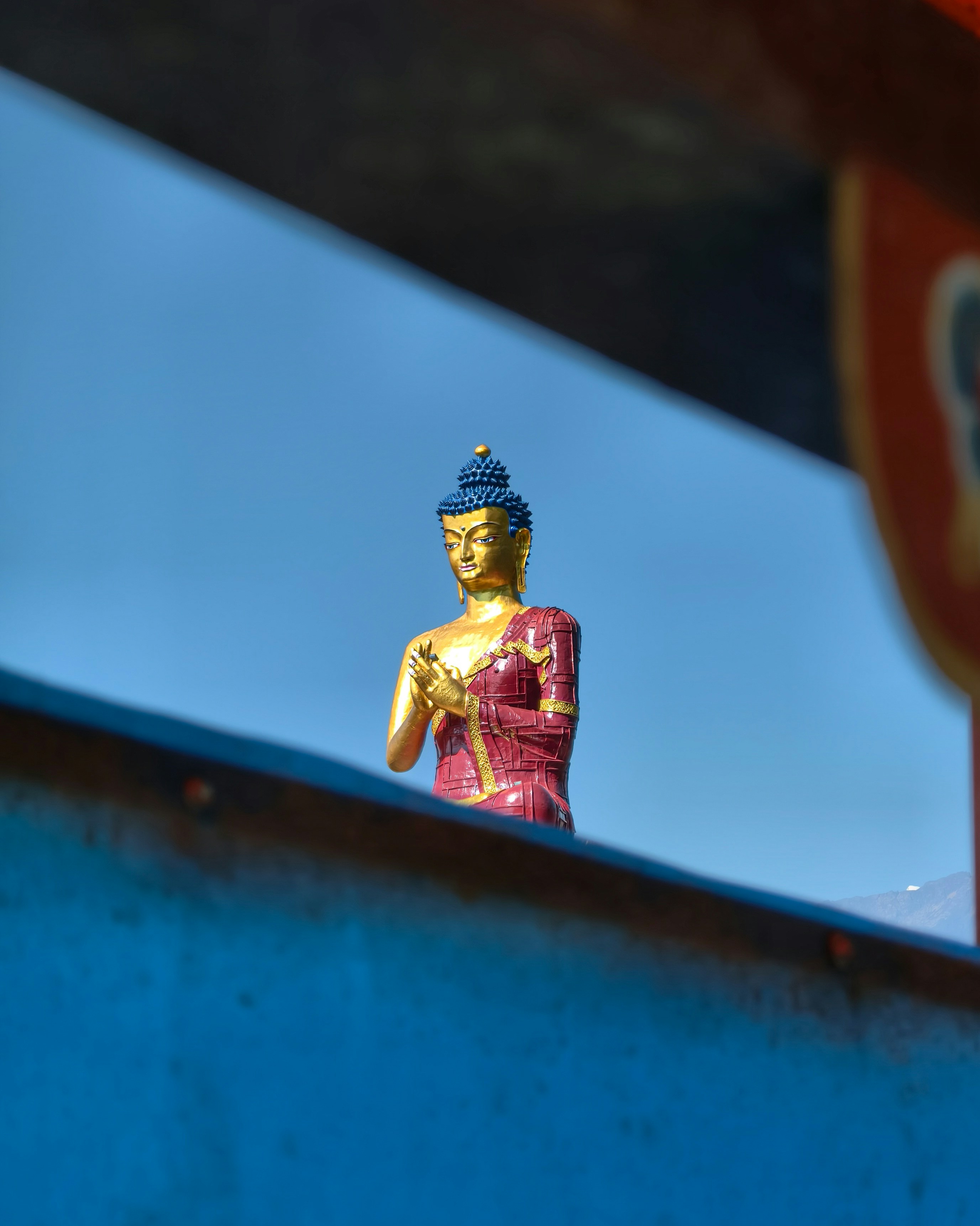 Golden buddha statue framed against a vibrant blue sky.