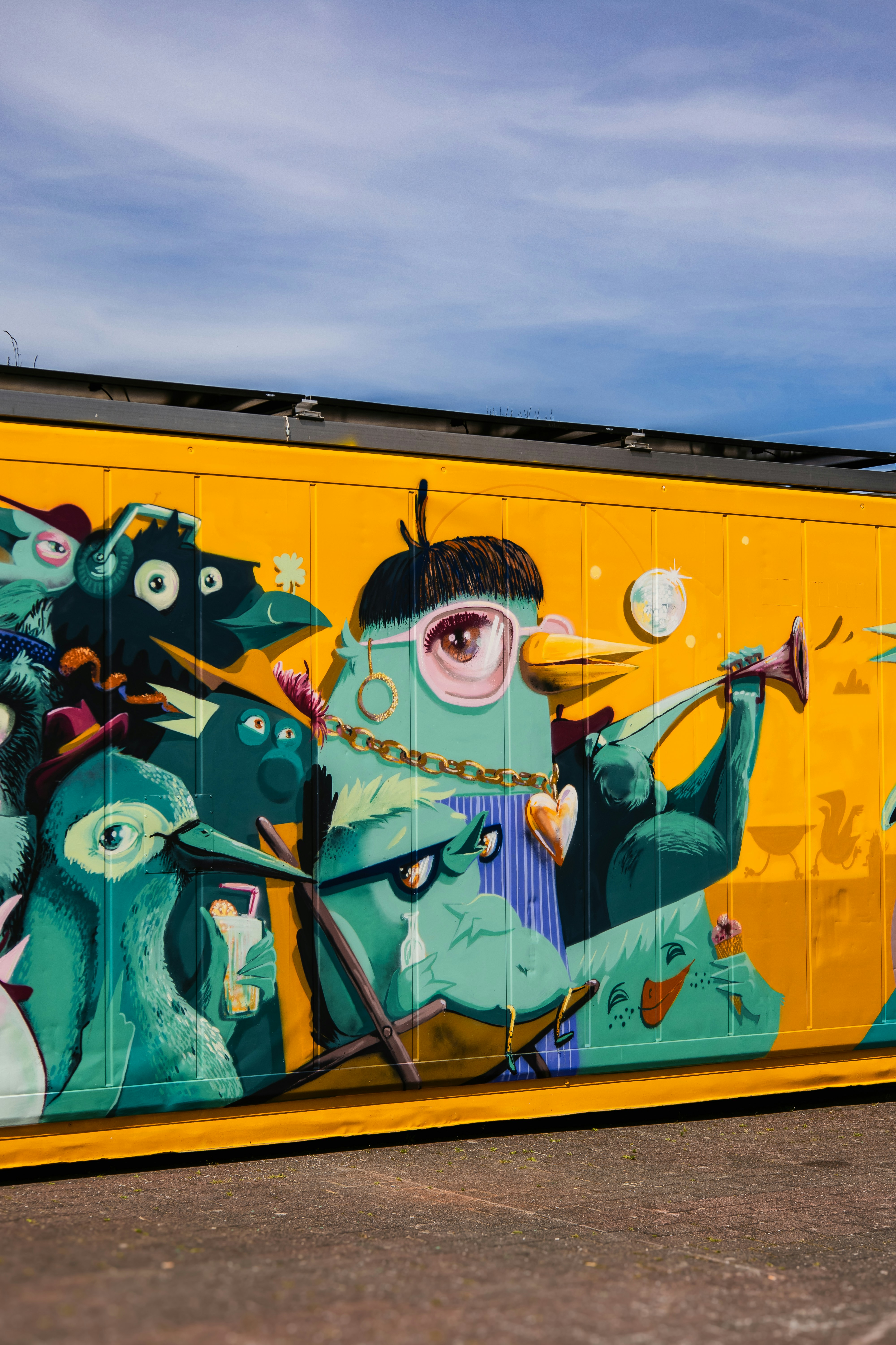 Vibrant mural of cartoon birds on a bright yellow wall.