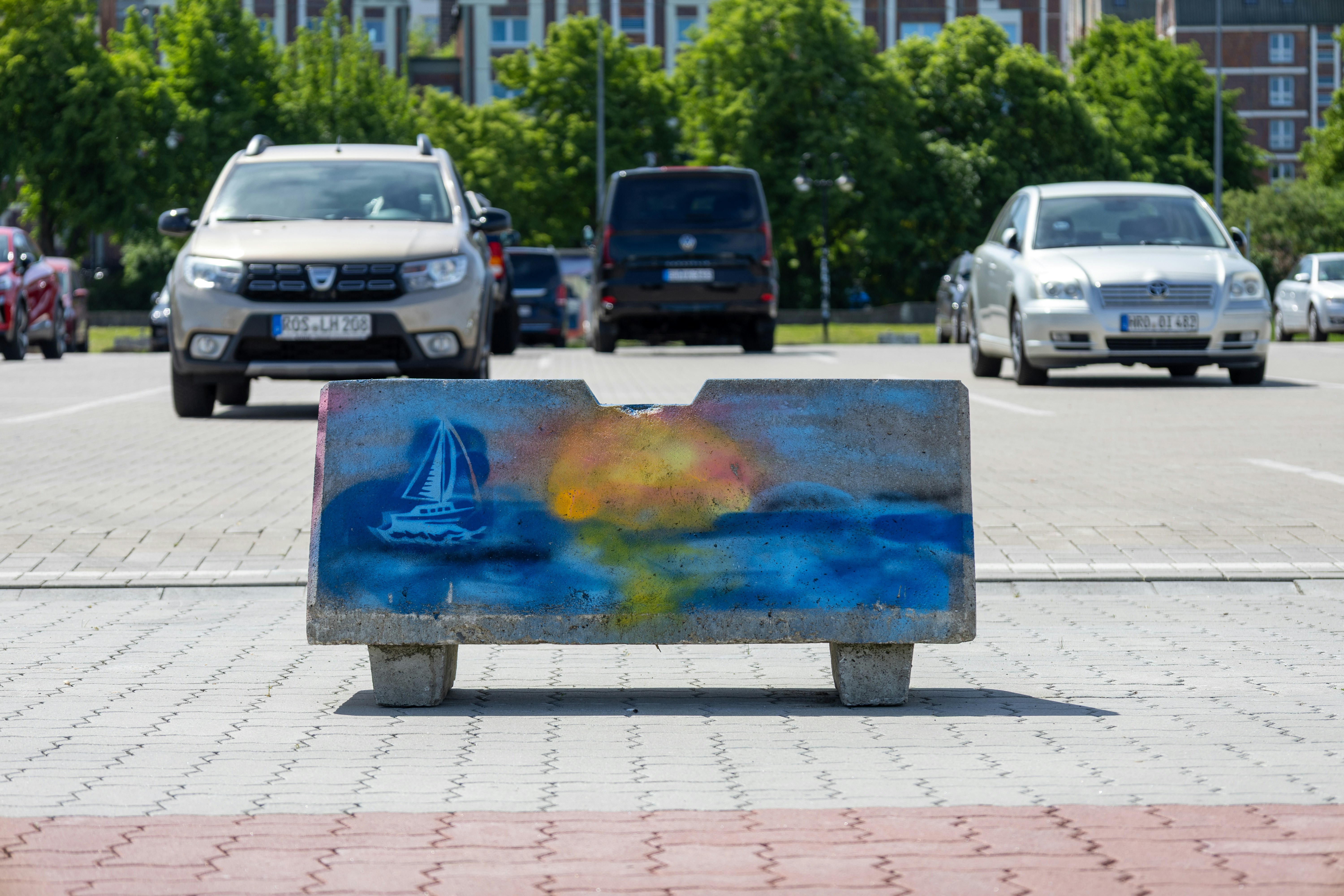 Concrete barrier with mushroom cloud graffiti in a car park.
