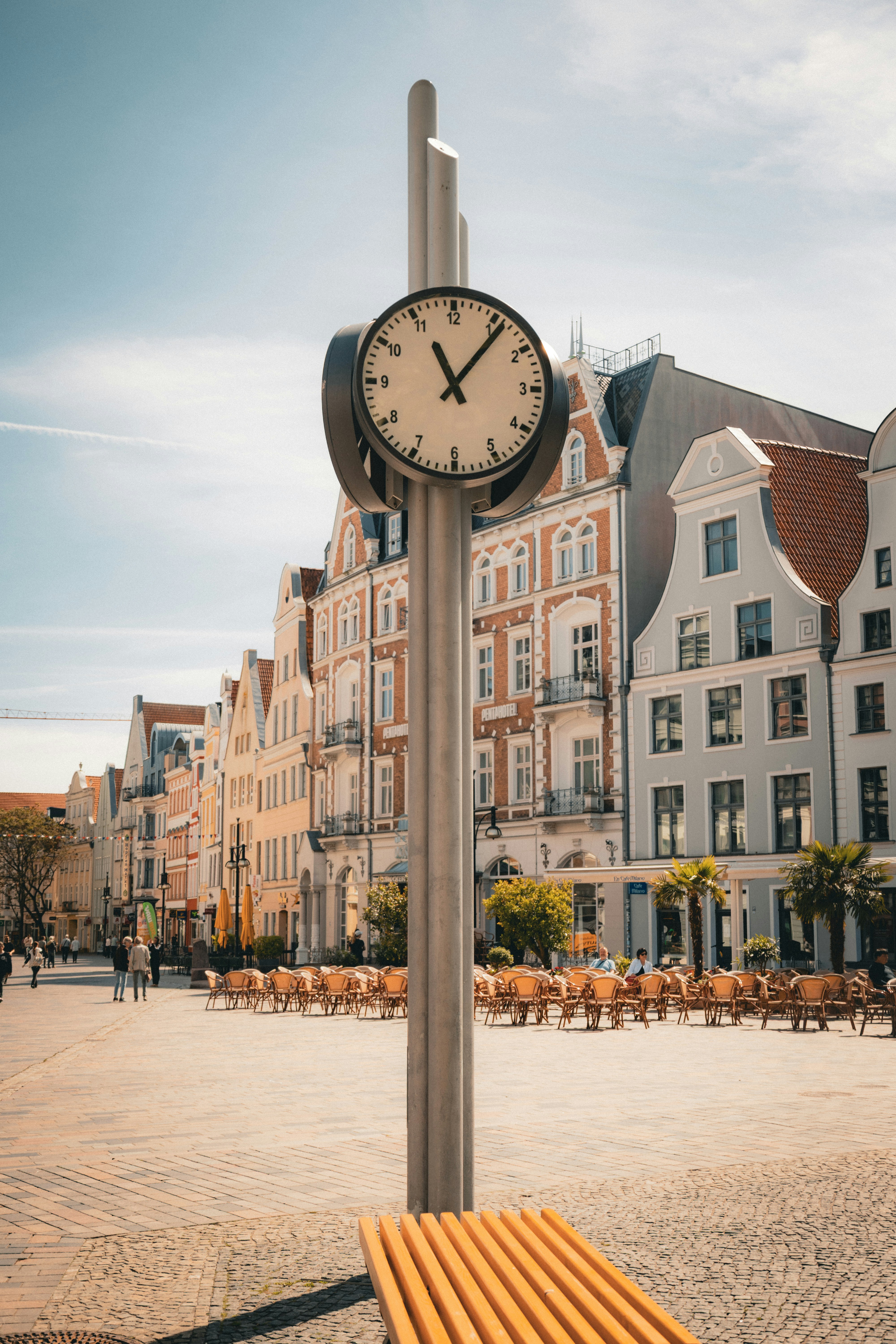 Modern clock and bench on a sunny european town square.