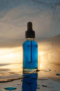 Blue dropper bottle with spilled liquid on a wet surface.
