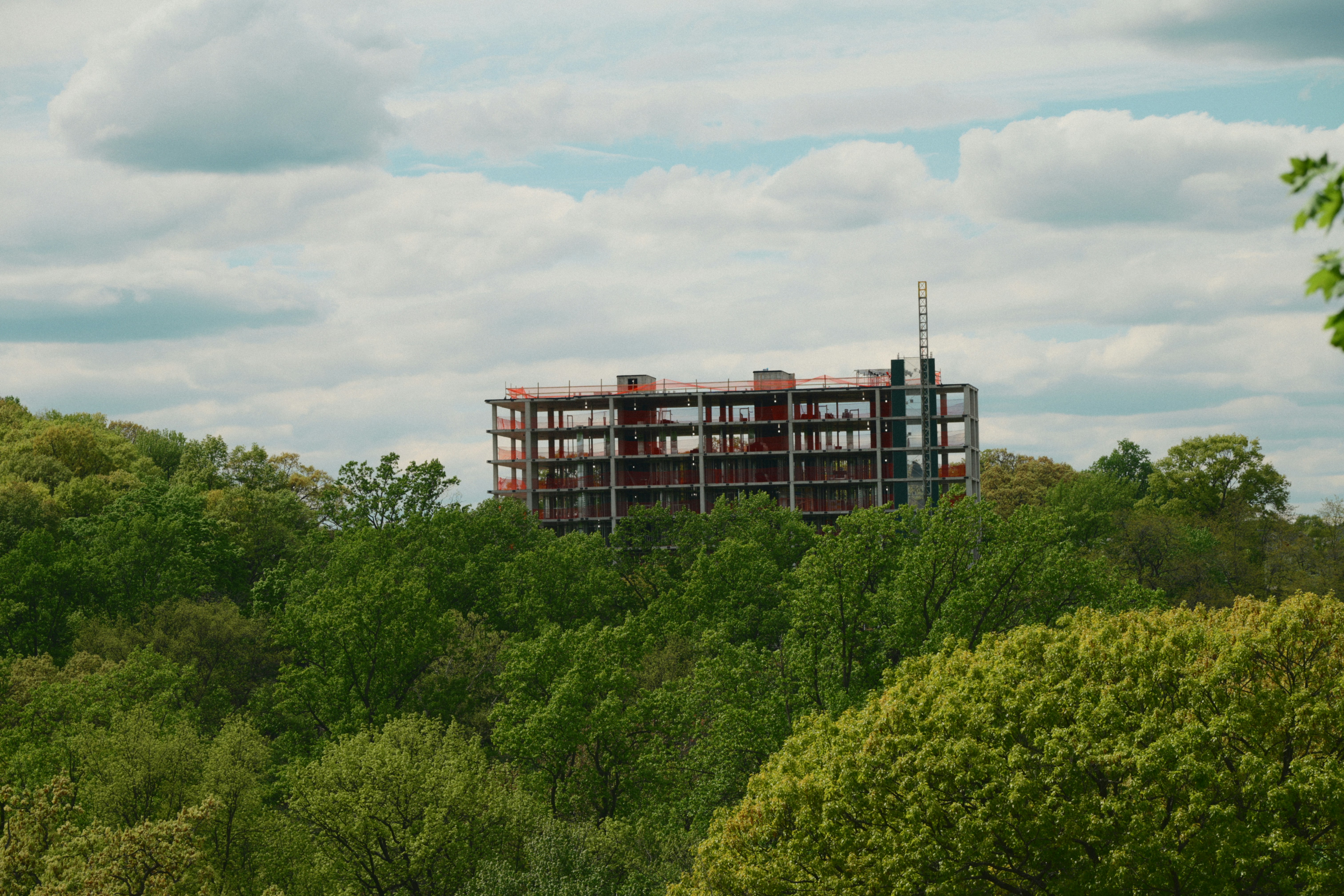 Unfinished building structure on a green forested hill.