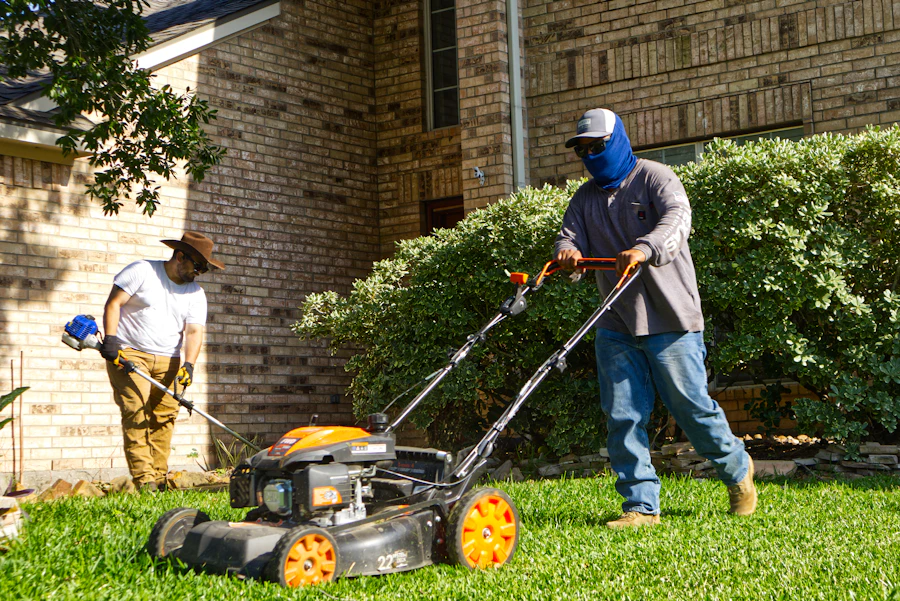 Two-person crew mowing and trimming a residential lawn