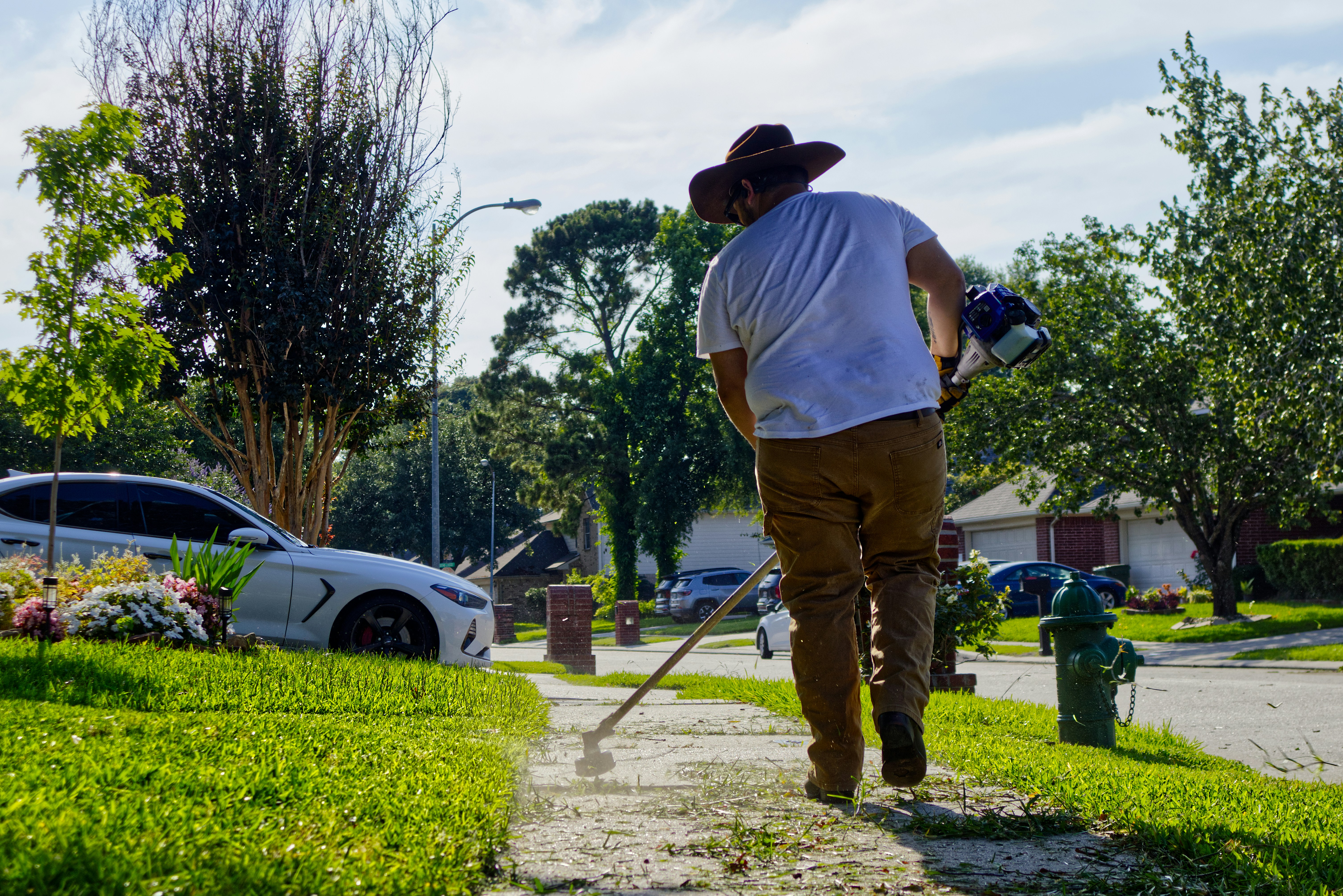 Professional landscapers cutting a clean, deep bed edge along a lush lawn