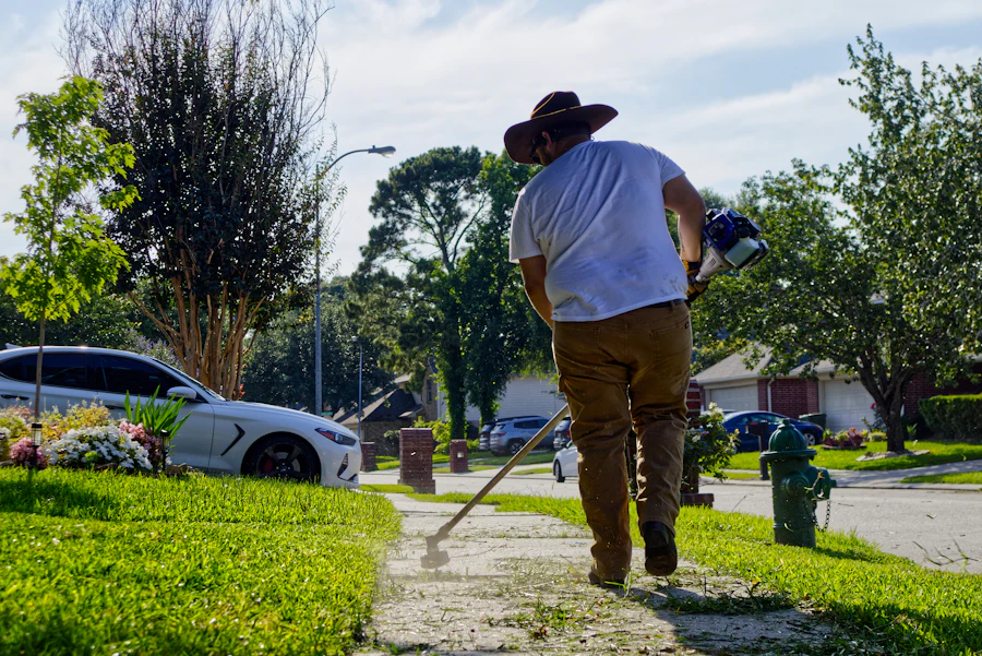 A man line trimming the grass edge along a sidewalk in front of a house.