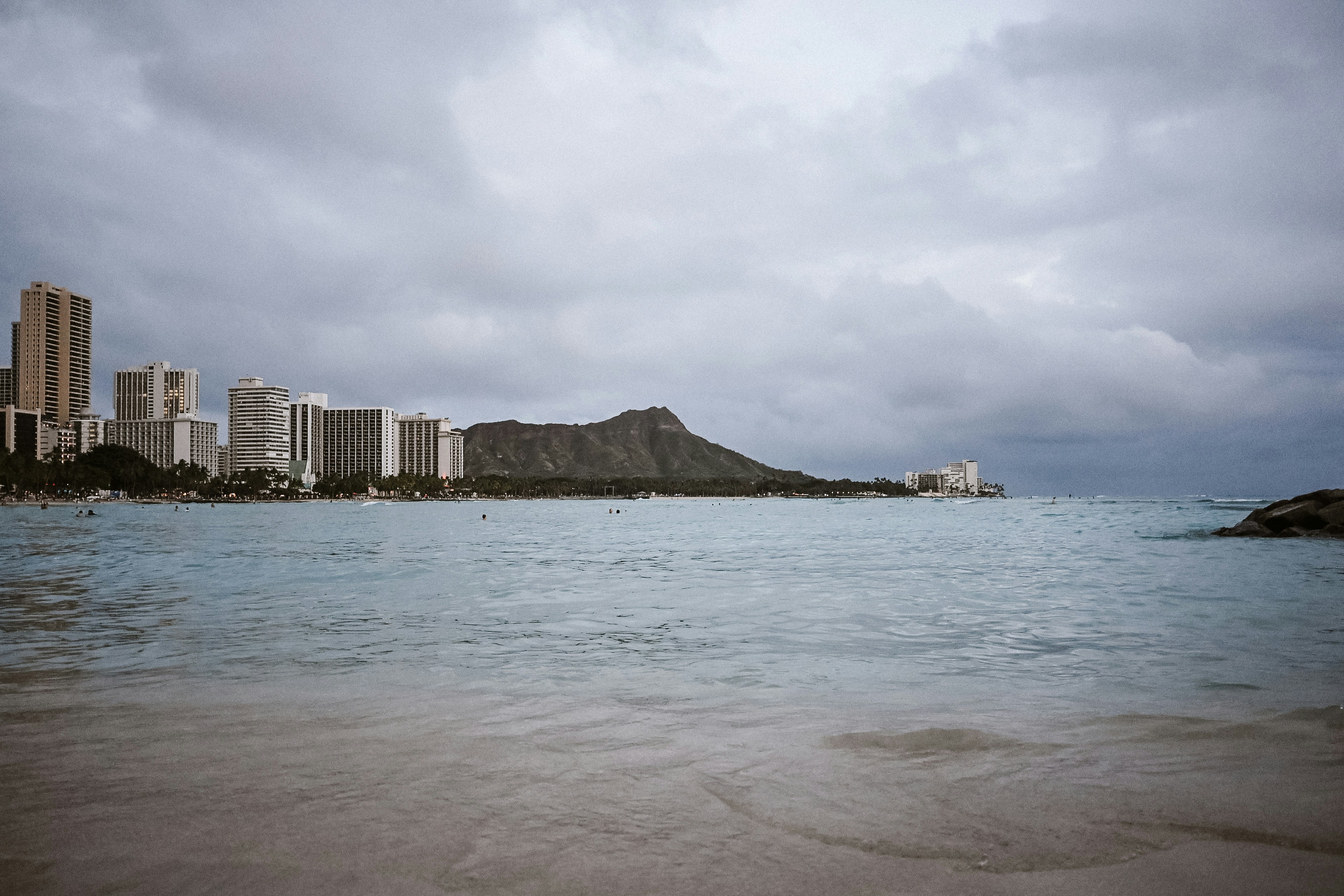 La spiaggia di Waikiki con lo skyline della città, la testa di diamante e il cielo nuvoloso.