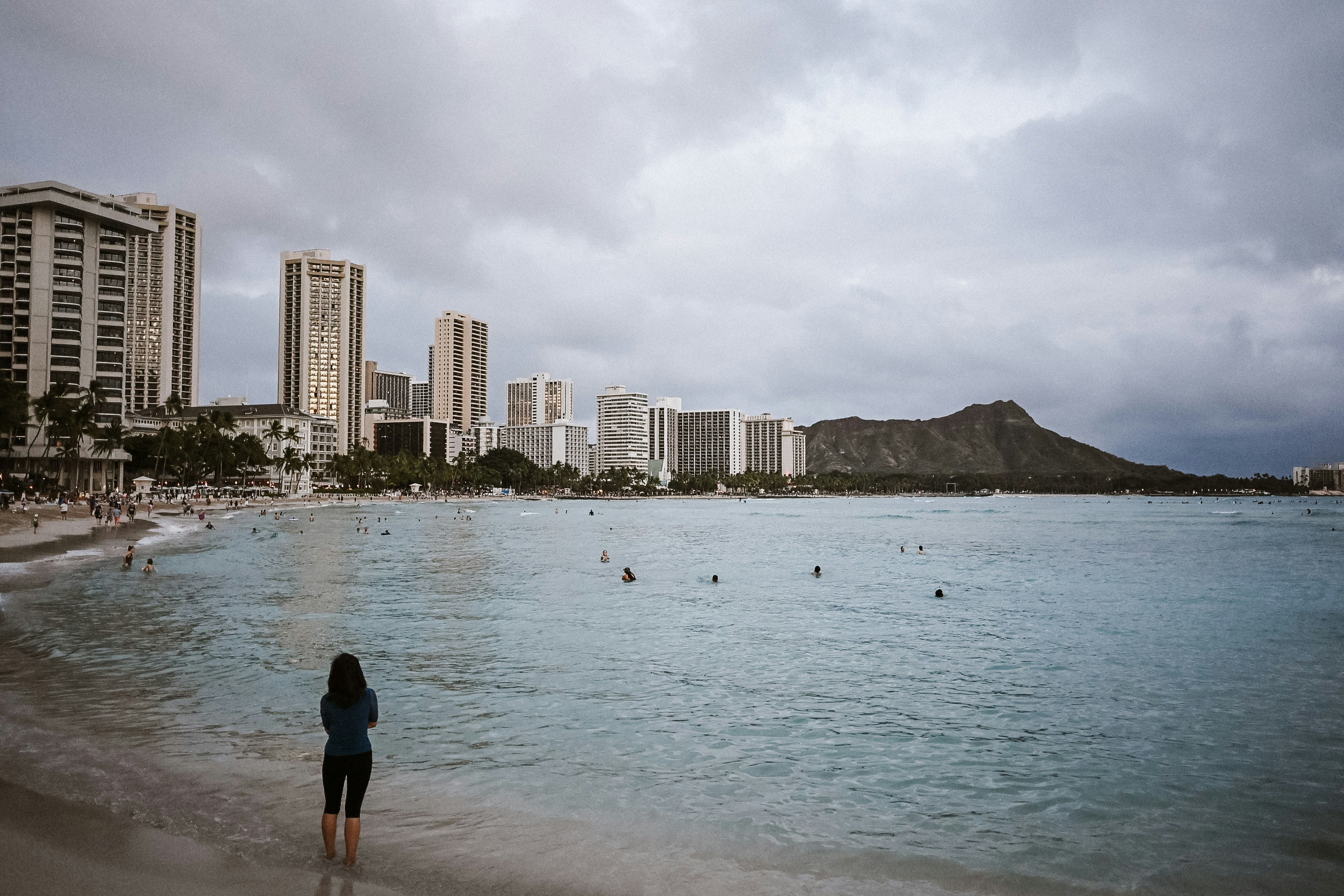 Donna sulla spiaggia di Waikiki con lo skyline di Honolulu e la testa di diamante.