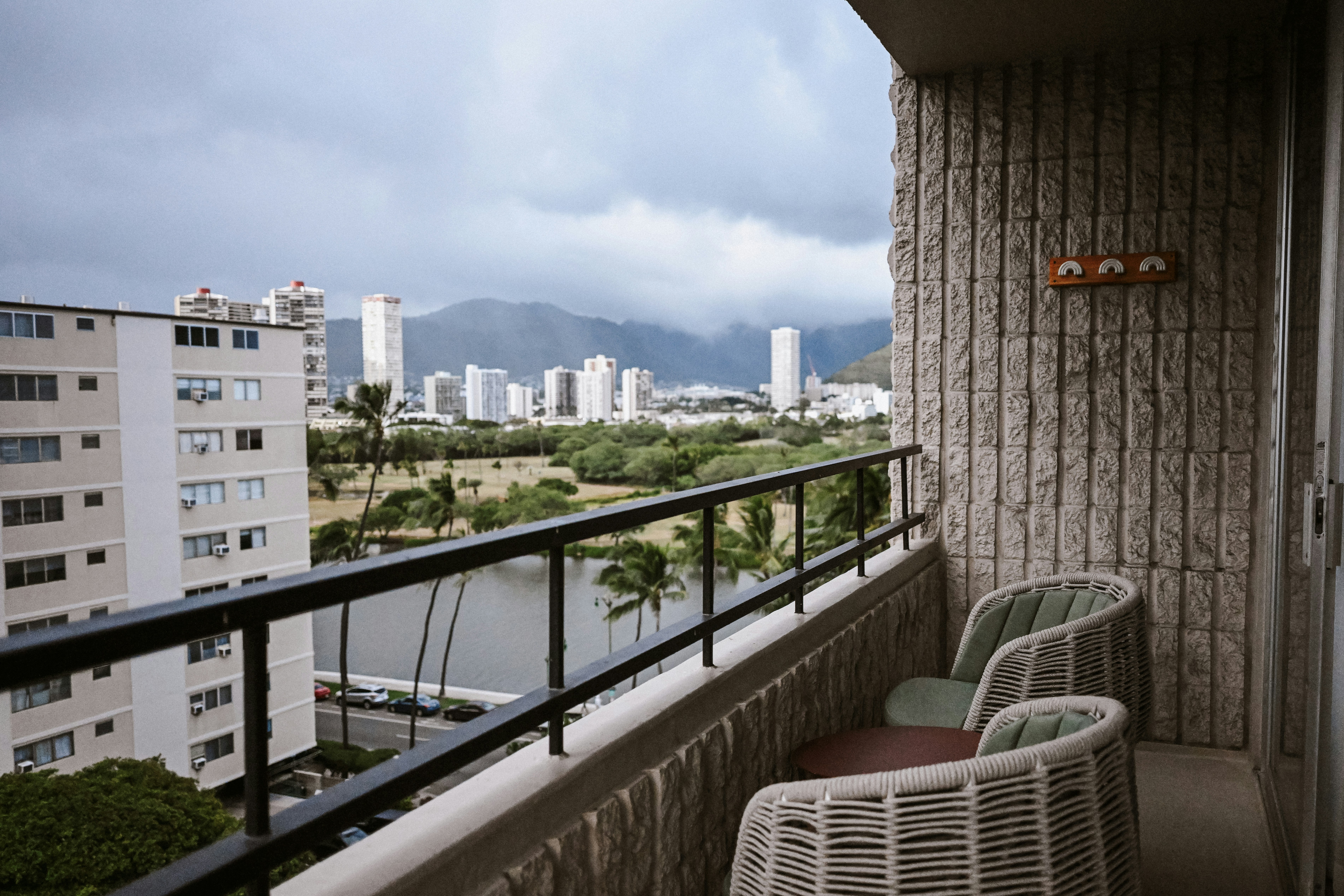Balcone con sedie che dà su una città, un canale e montagne.