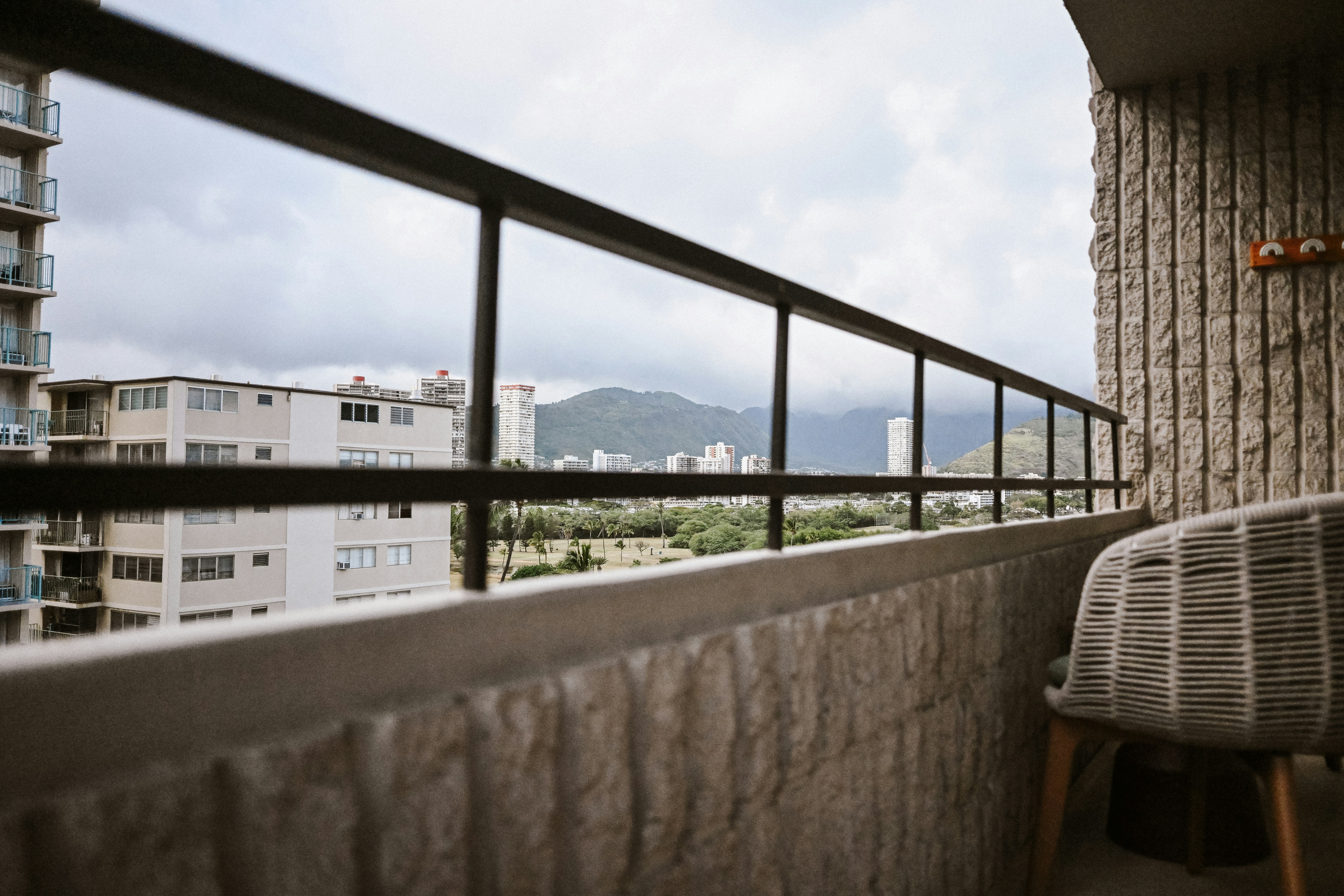 Vista dal balcone su edifici cittadini e montagne sotto il cielo nuvoloso.