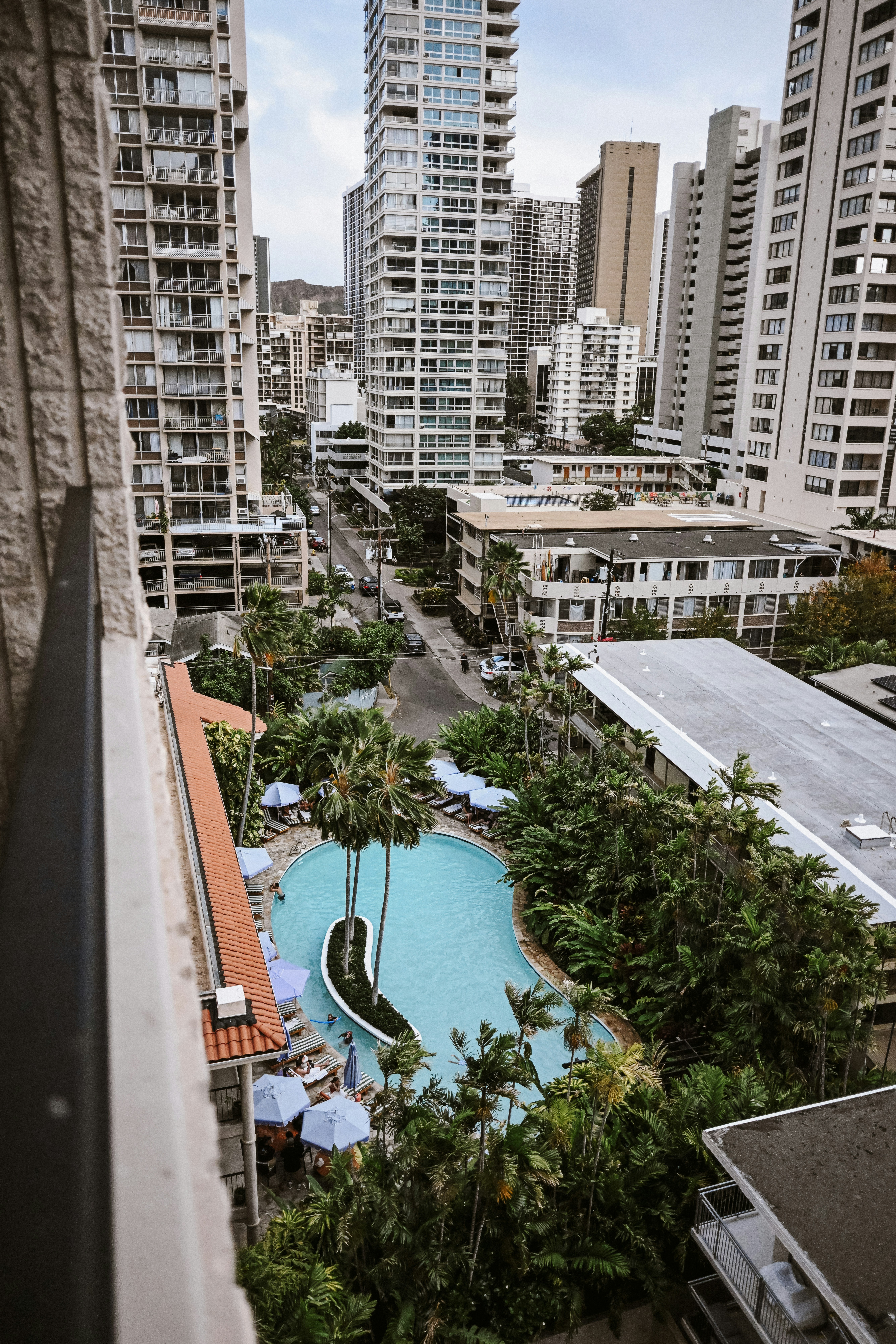 Piscina urbana da resort circondata da grattacieli e palme.