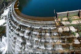 Water cascades over a curved concrete dam.