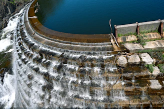 Water cascades over a curved concrete dam.
