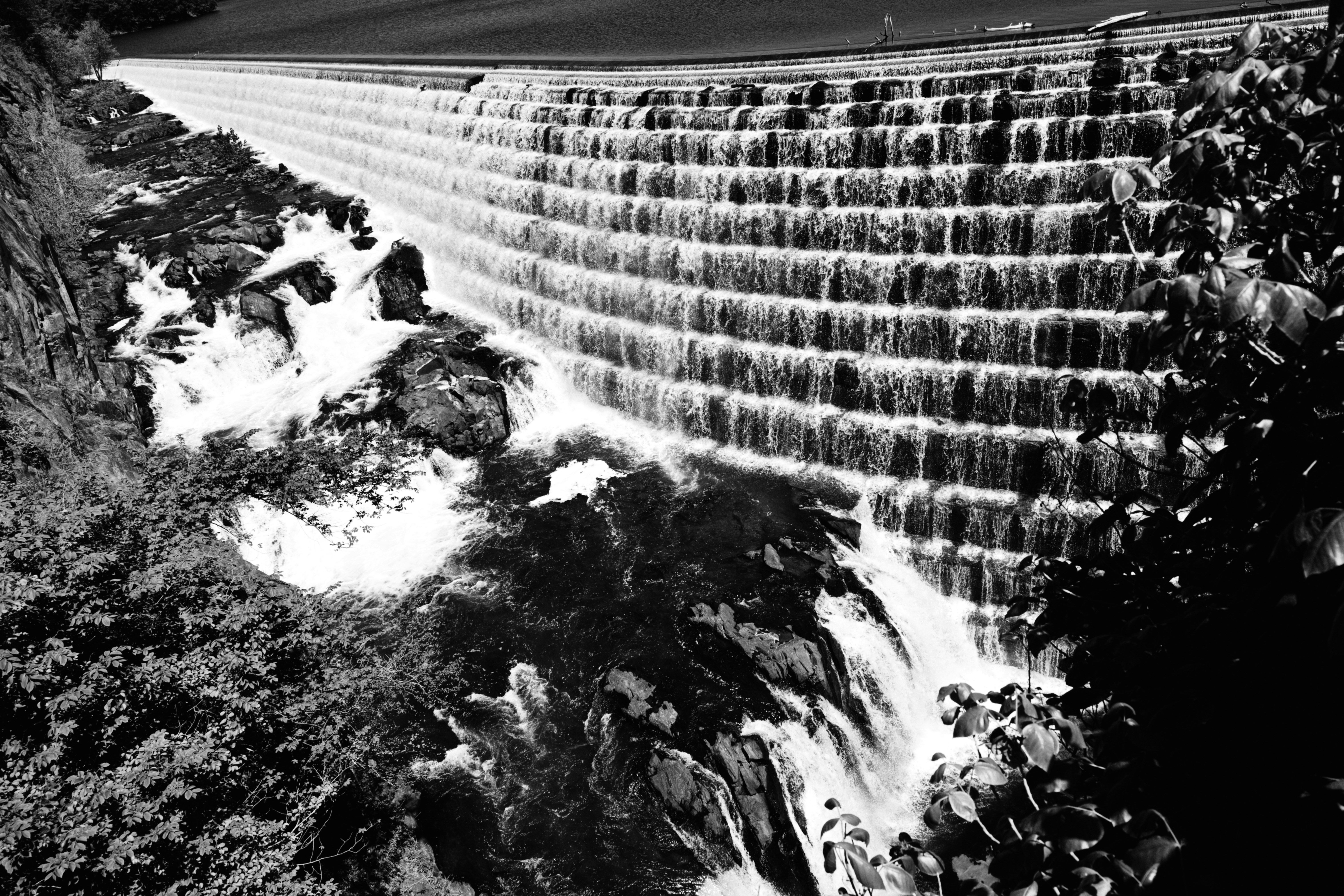 A large stepped dam with water flowing over its face
