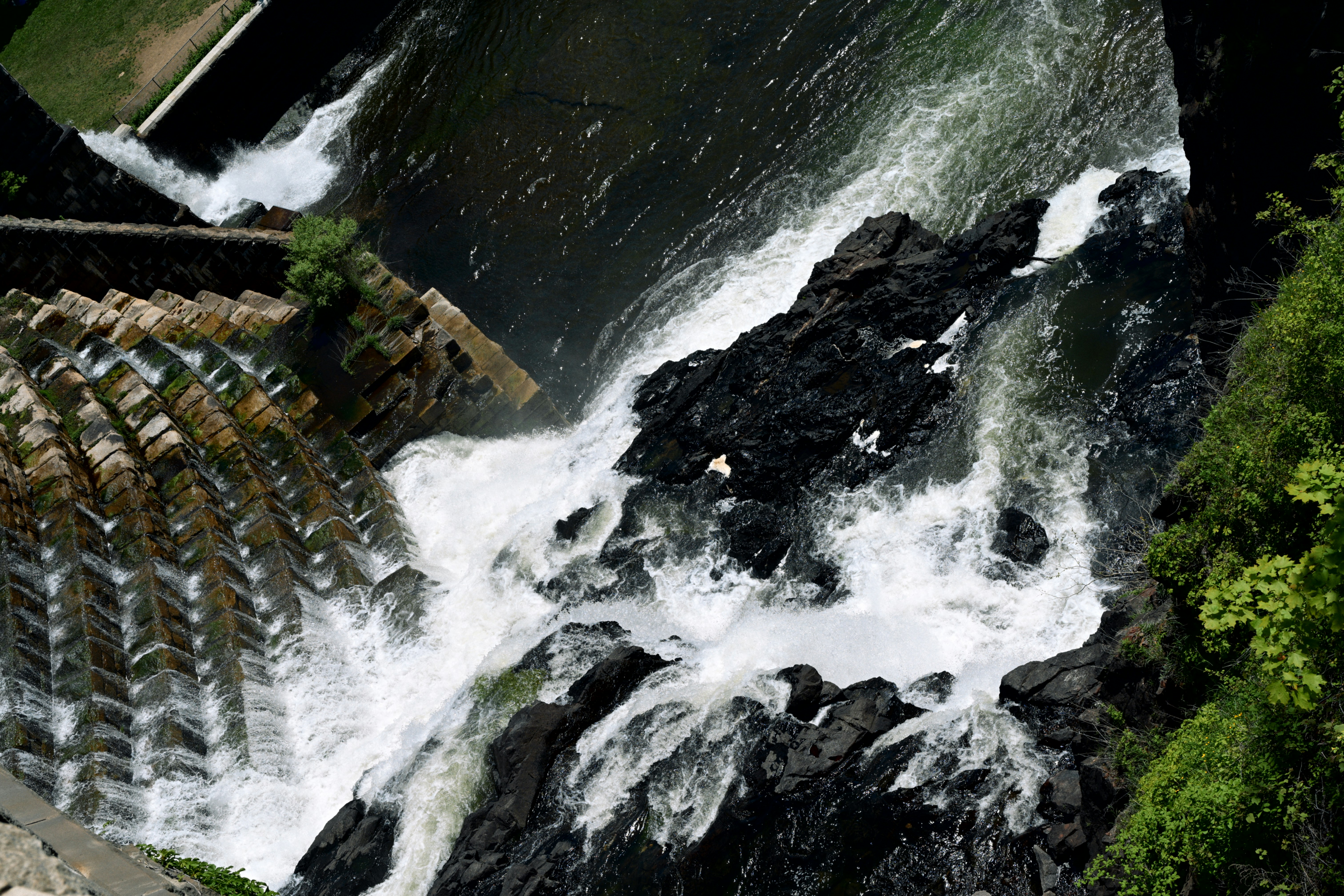 Water cascades over dark rocks from a dam