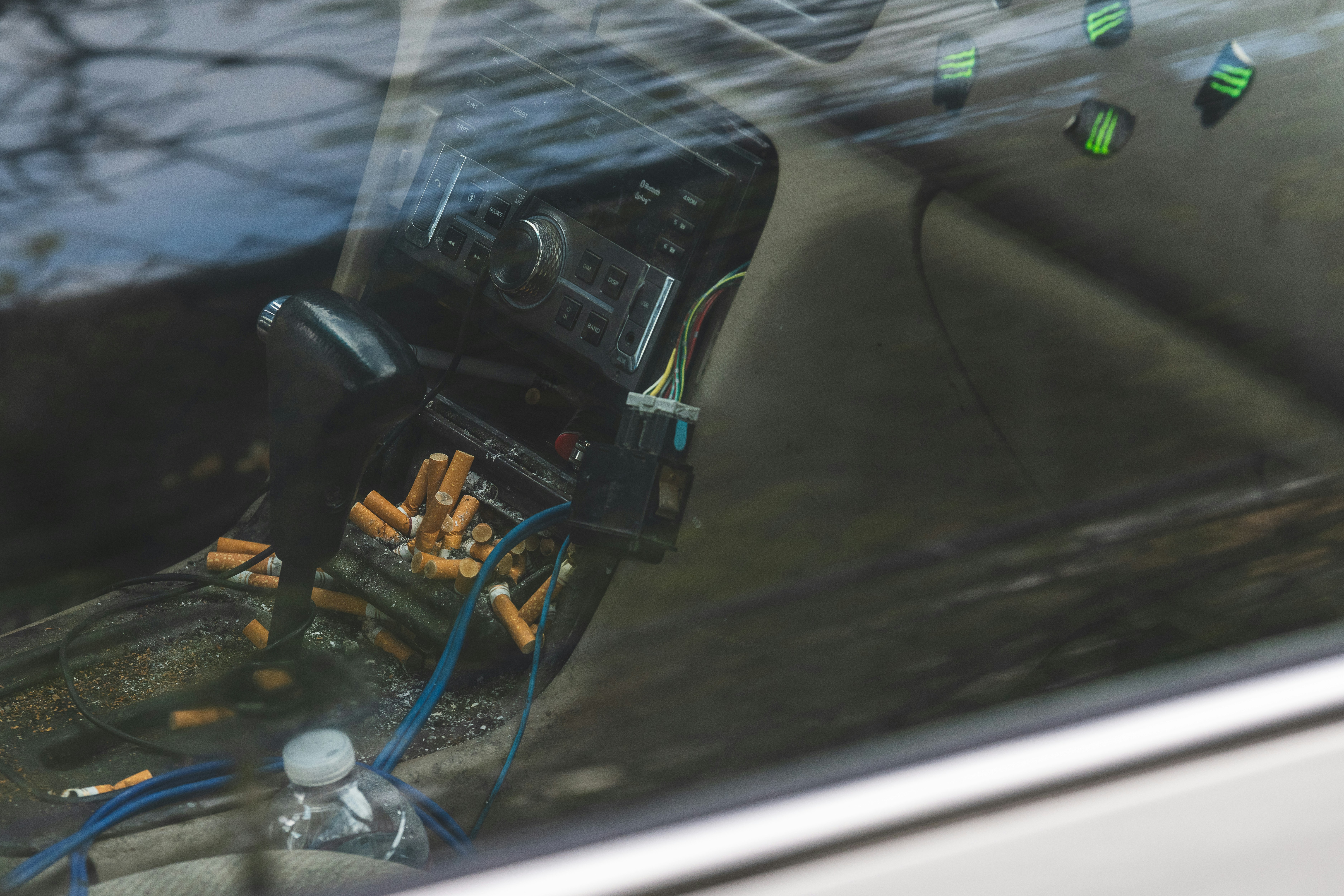 Car interior with exposed radio and many cigarette butts.