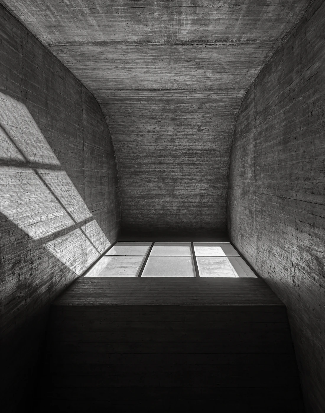 Sunlight falling through a window into a board-marked concrete room