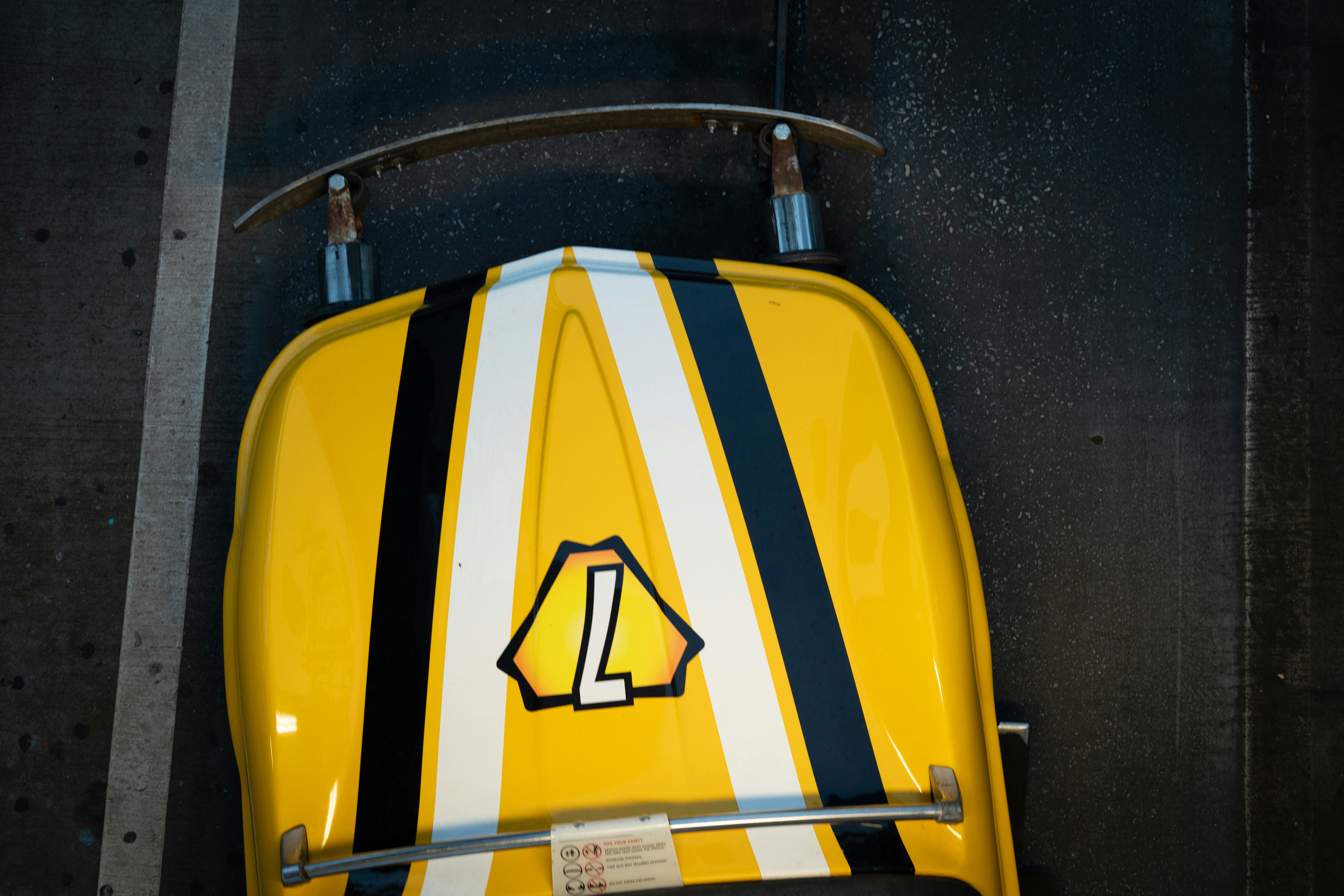 Kereta luncur kuning dengan garis-garis hitam, putih dan logo "l".