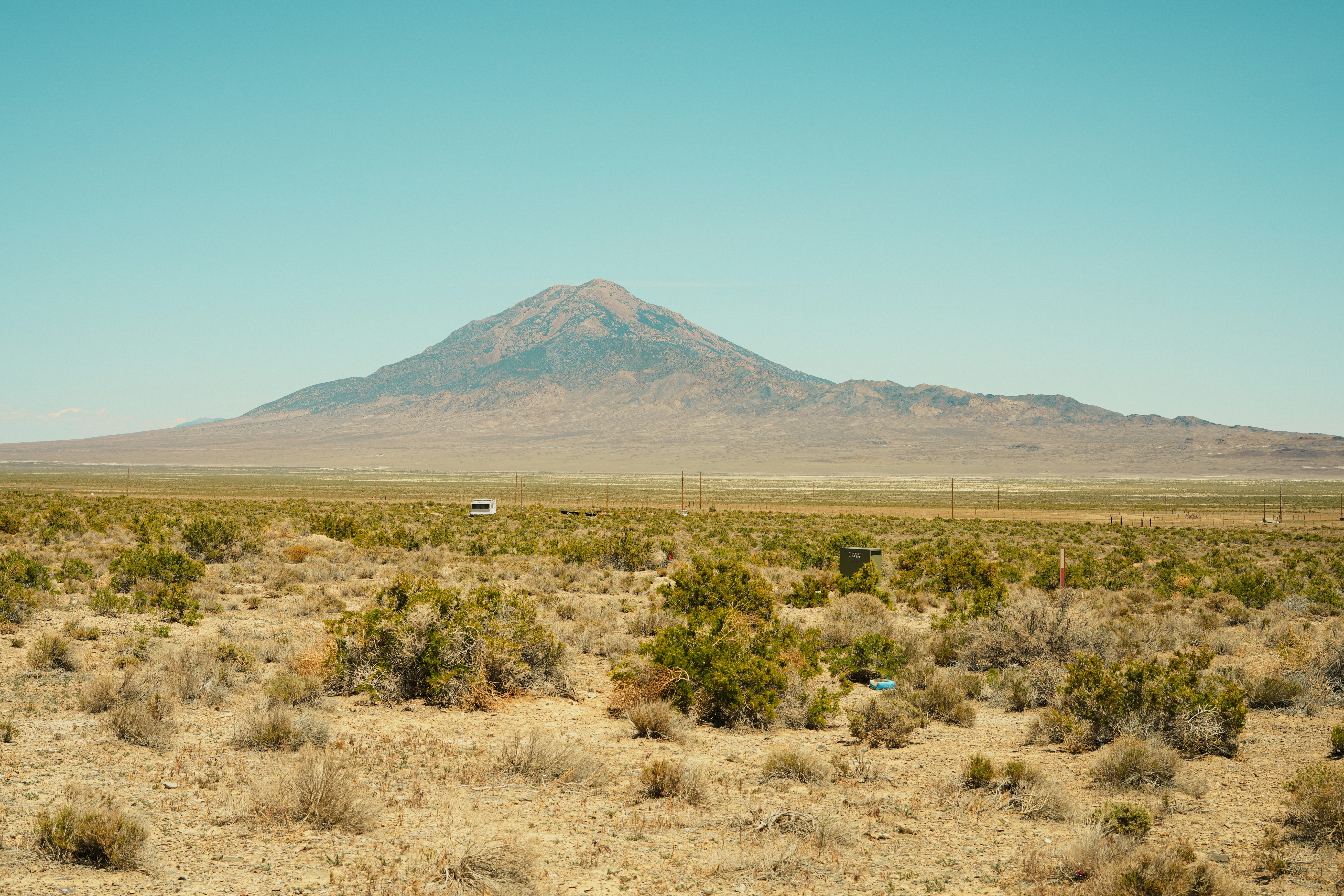 Deserto vasto com uma montanha e um pequeno veículo.