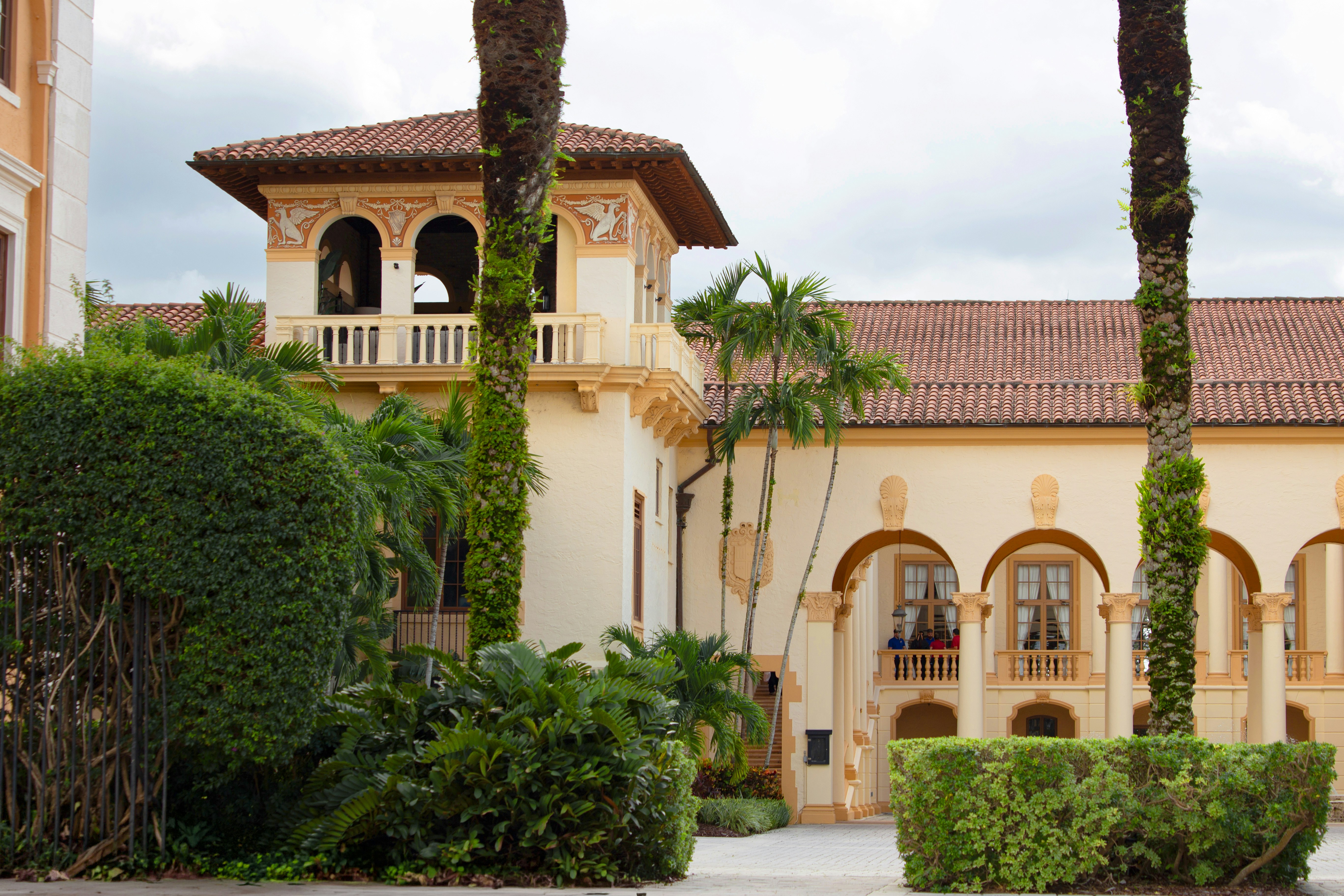Ornate building with a tower, archways, and lush tropical landscaping.
