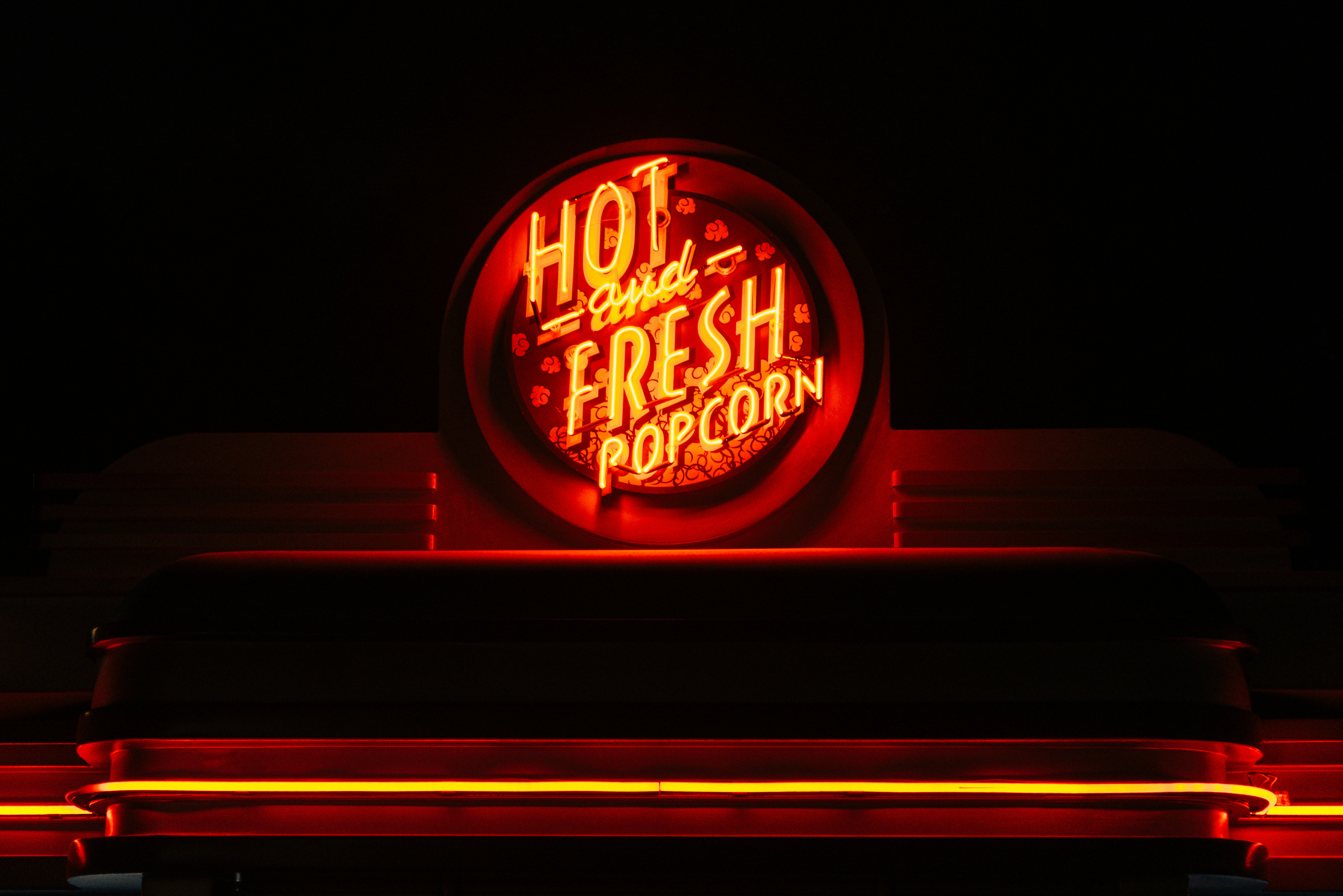 Tanda neon merah bersinar mengiklankan popcorn panas dan segar.