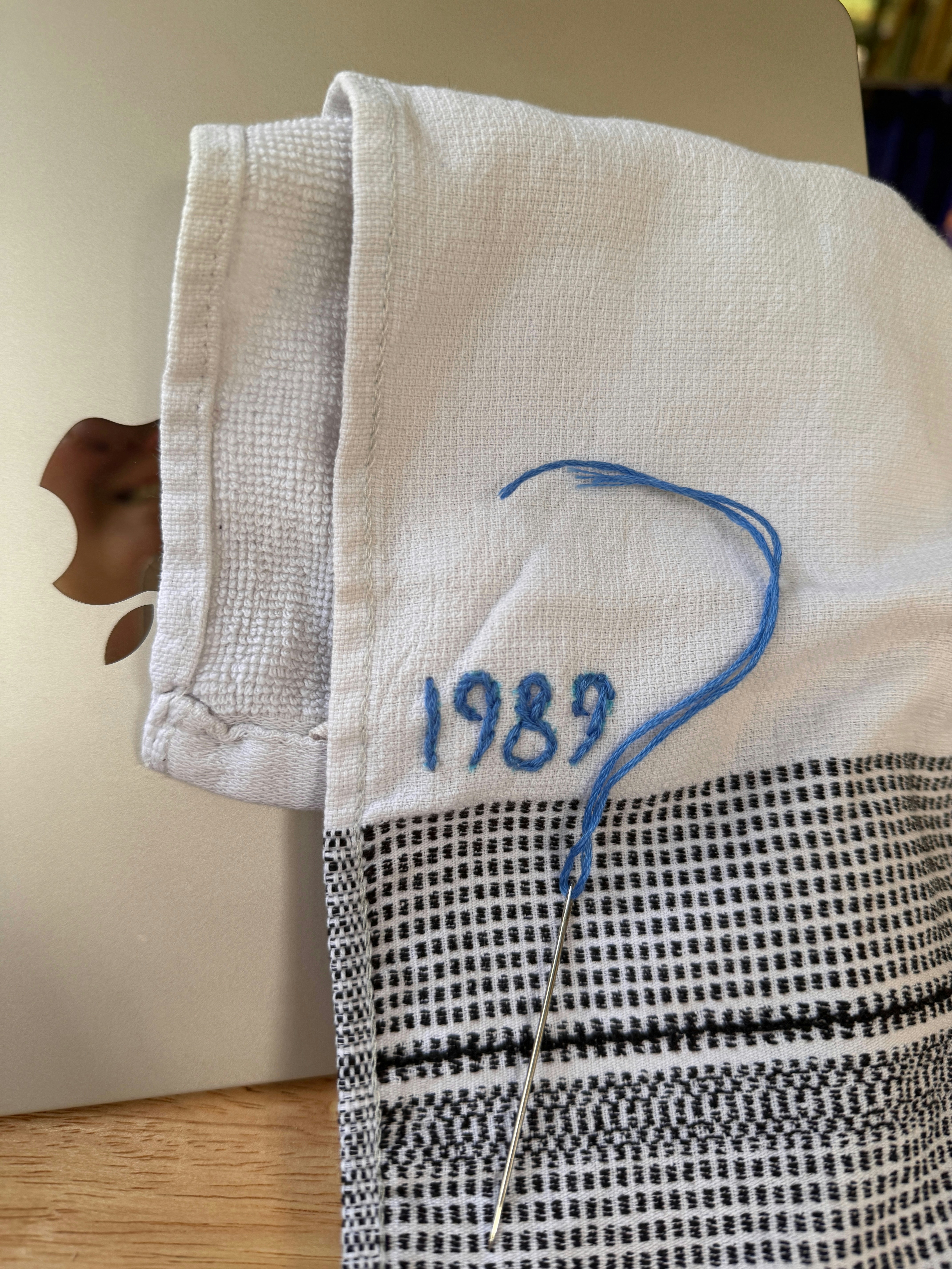Mit Nadel und Laptop auf ein Handtuch "1989" gestickt.