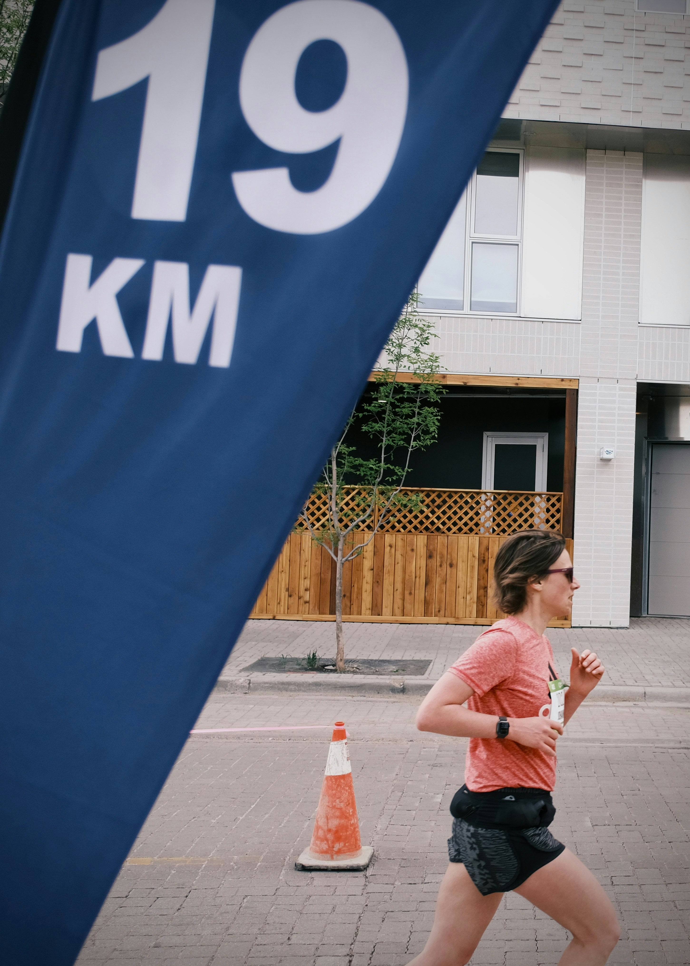 Woman running past a blue 19 km race marker