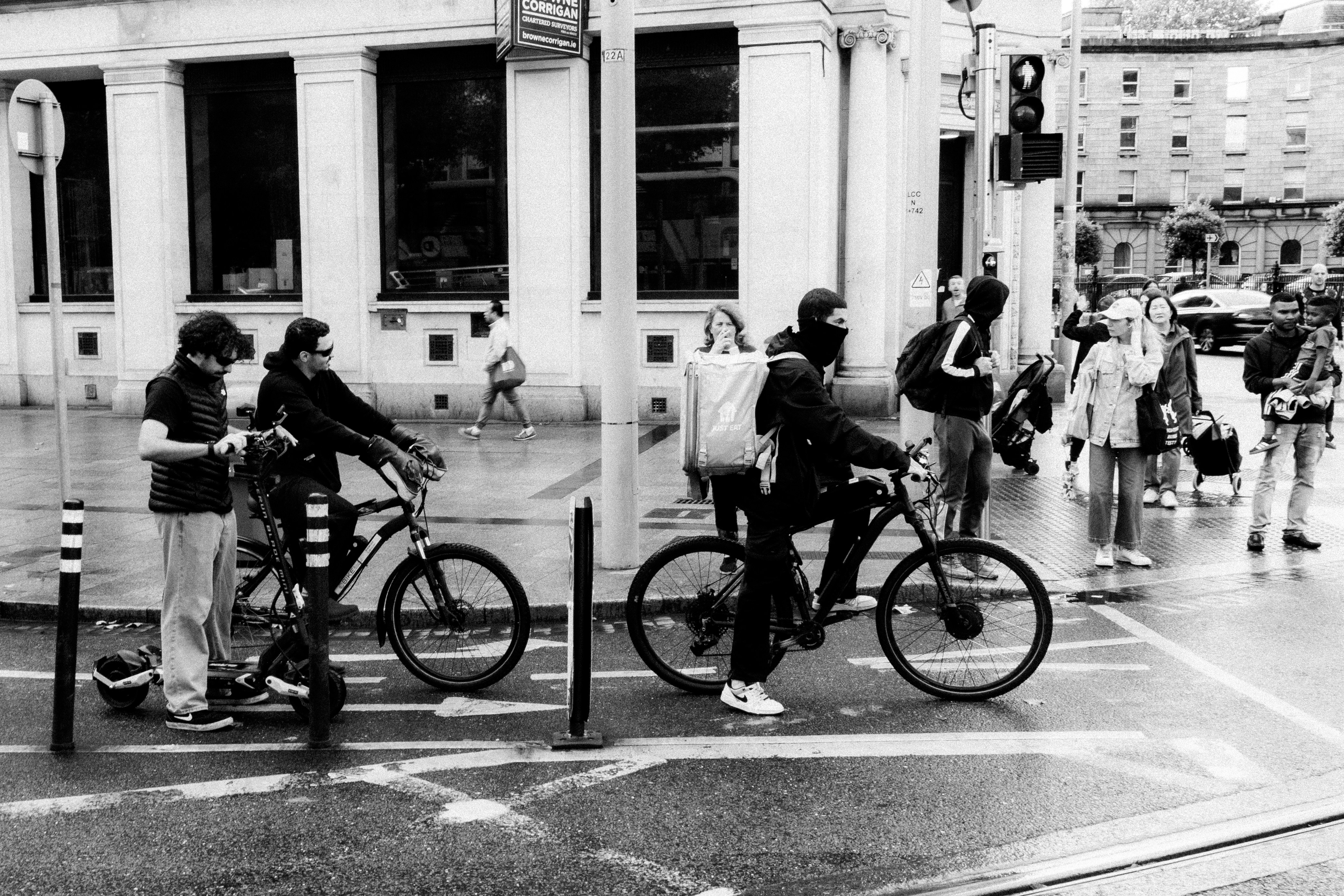 People on bicycles and pedestrians at a city intersection.