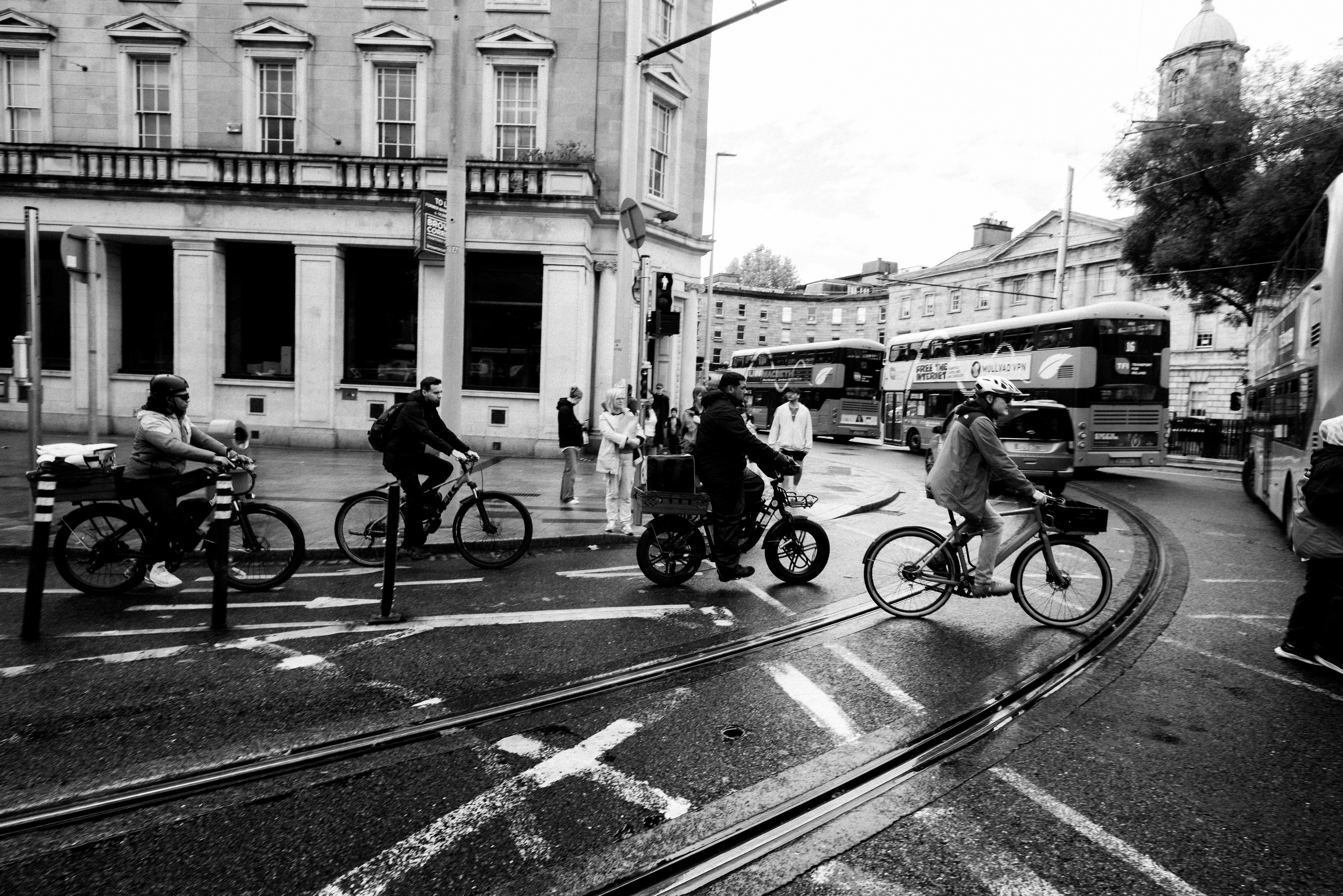 Cyclists navigate a busy city intersection with tram lines.
