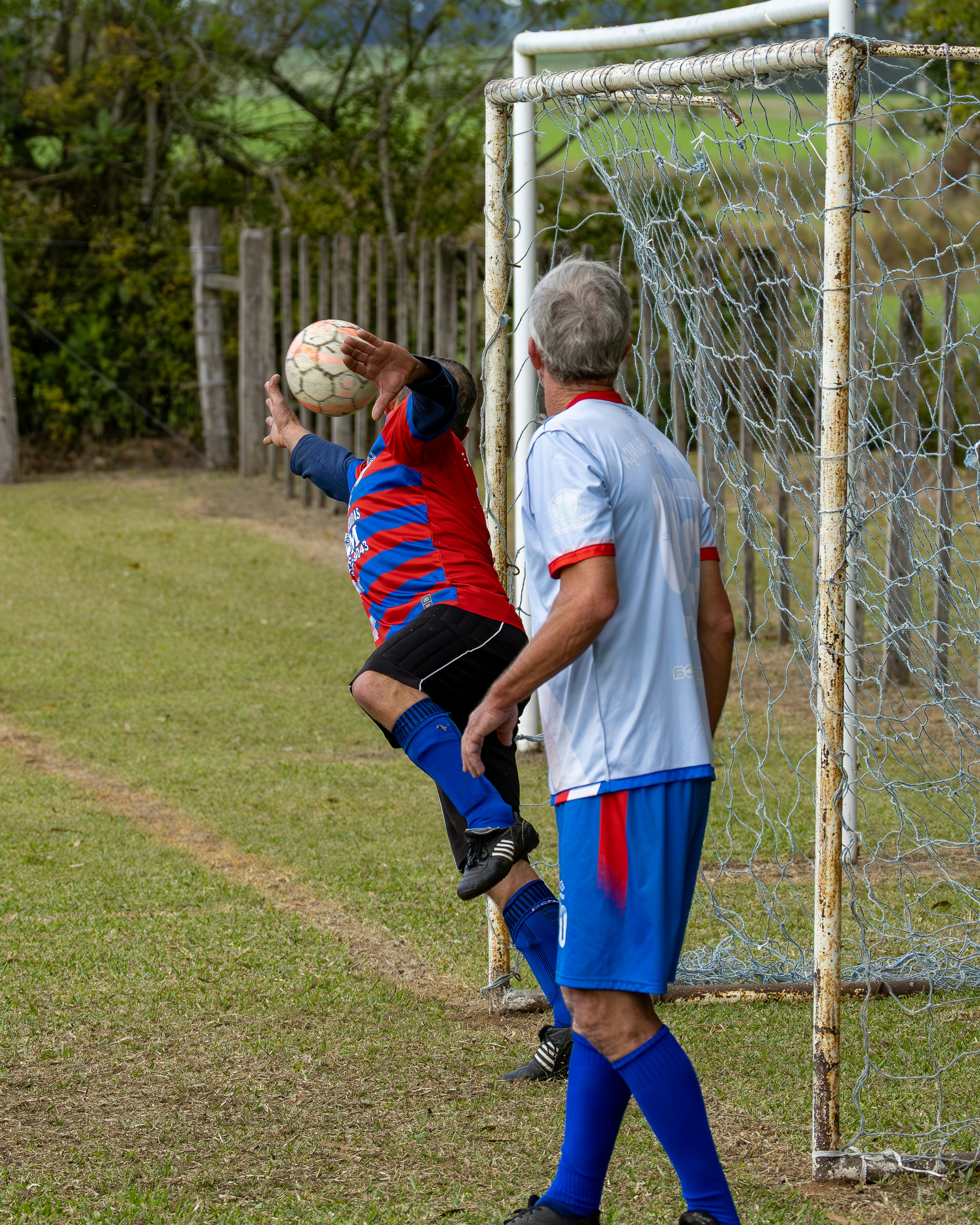 Soccer goalie jumps to catch the ball near the goal