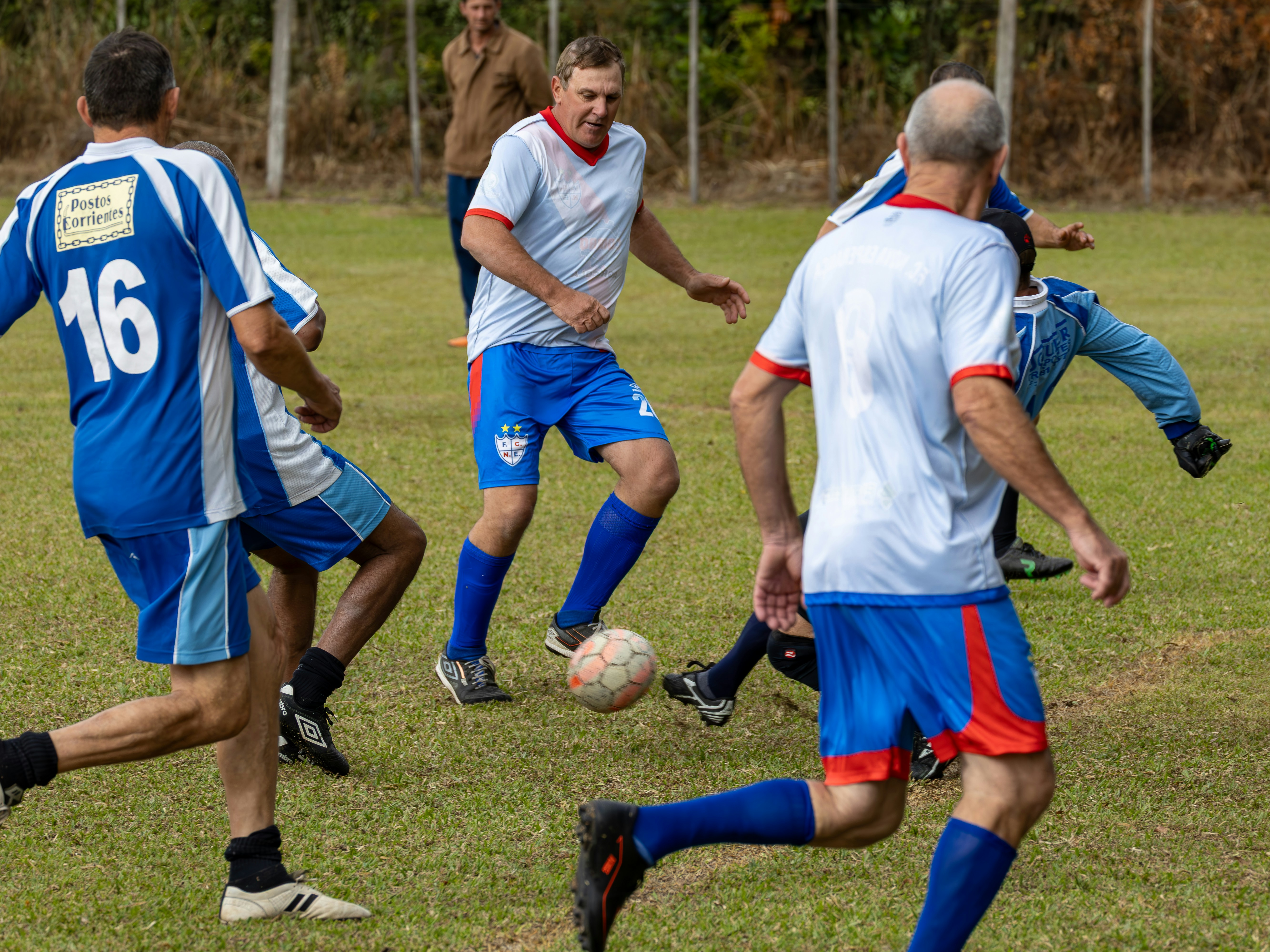 Pria dewasa bermain sepak bola di lapangan berumput.