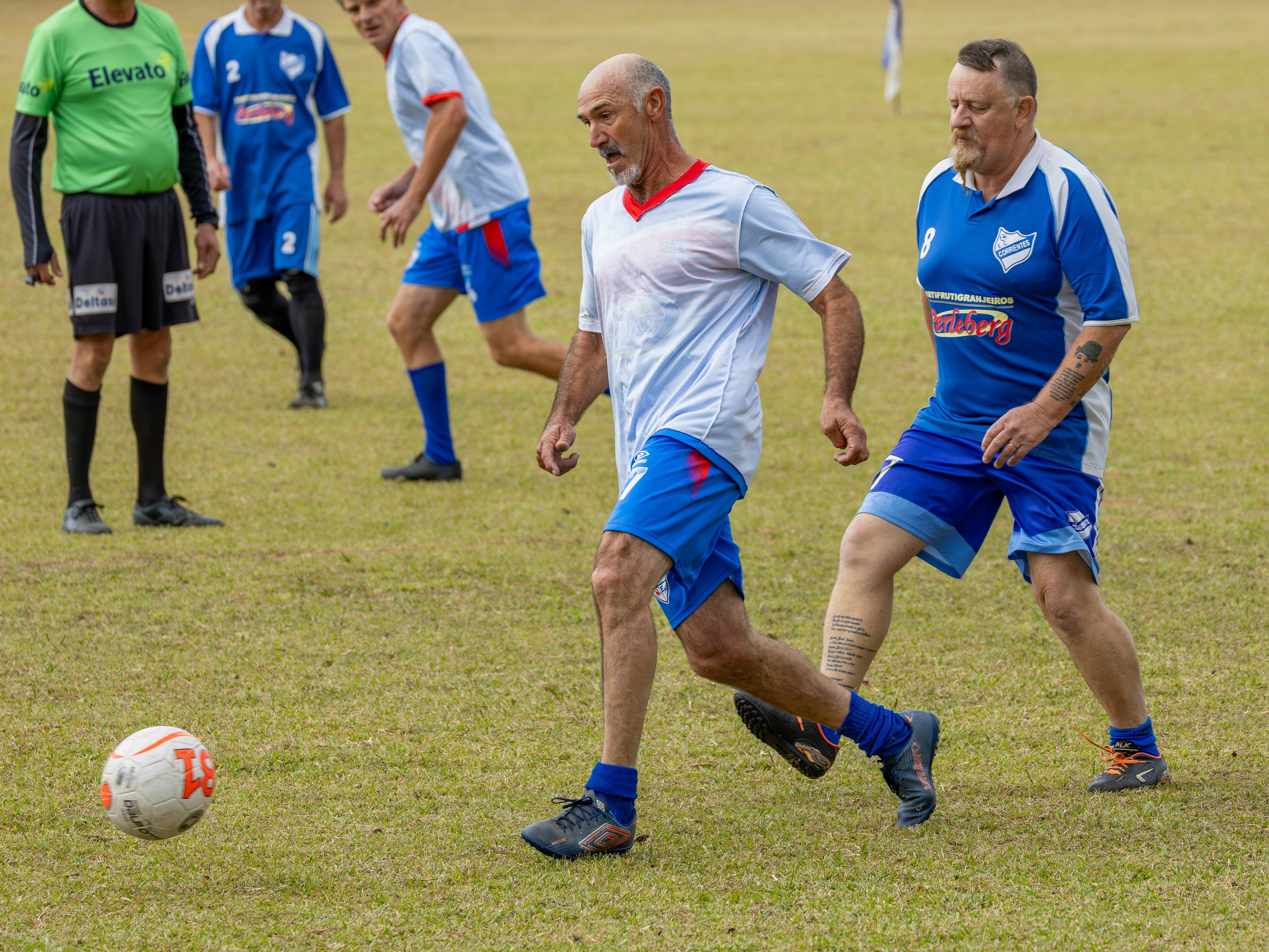 Pria bermain sepak bola di lapangan berumput.