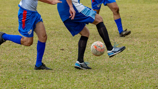 Soccer players juggling a ball on a green field.