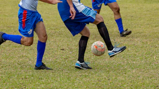 Soccer players juggling a ball on a green field.