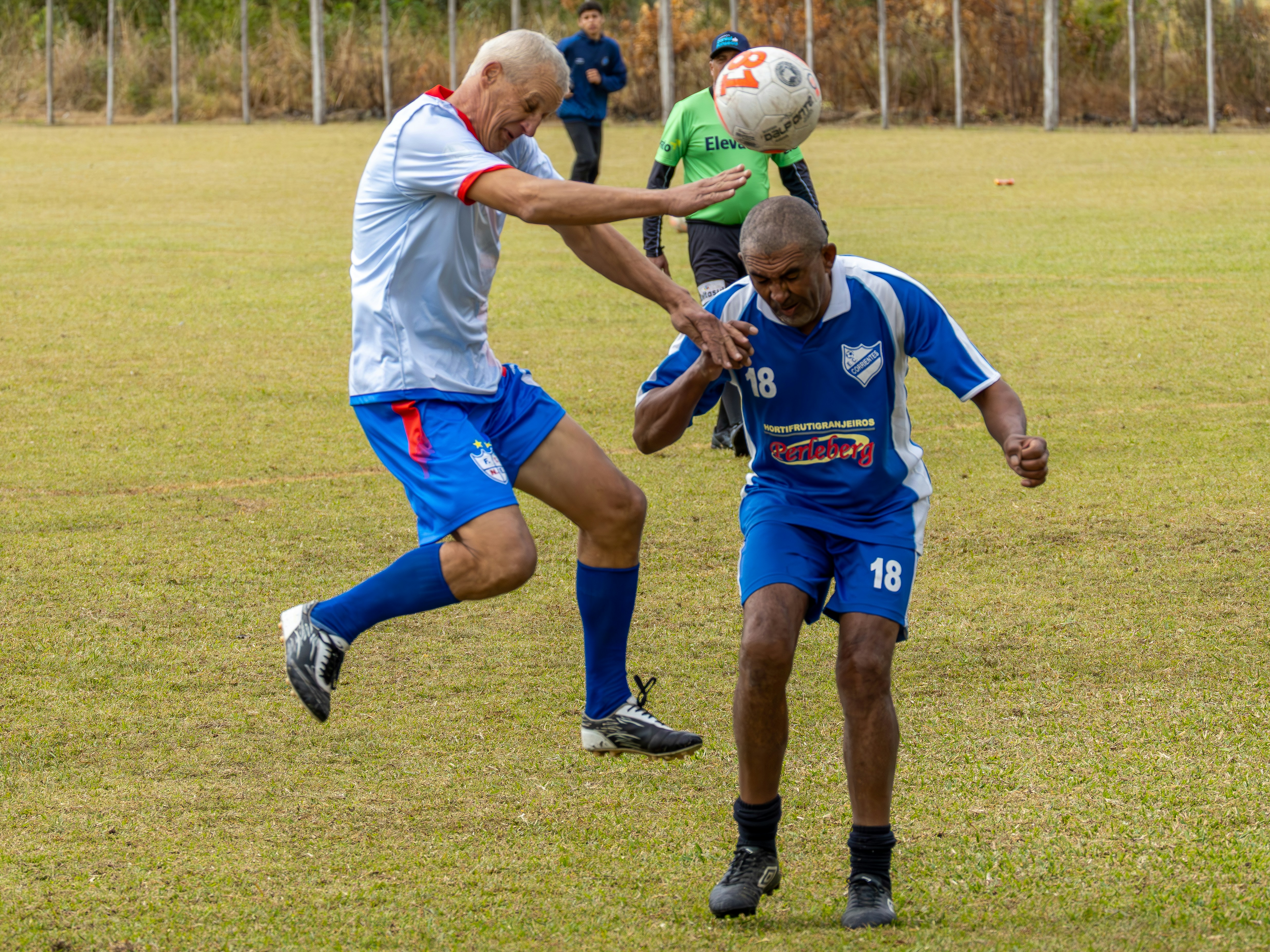 Dua pria melompat untuk mengarahkan bola sepak.