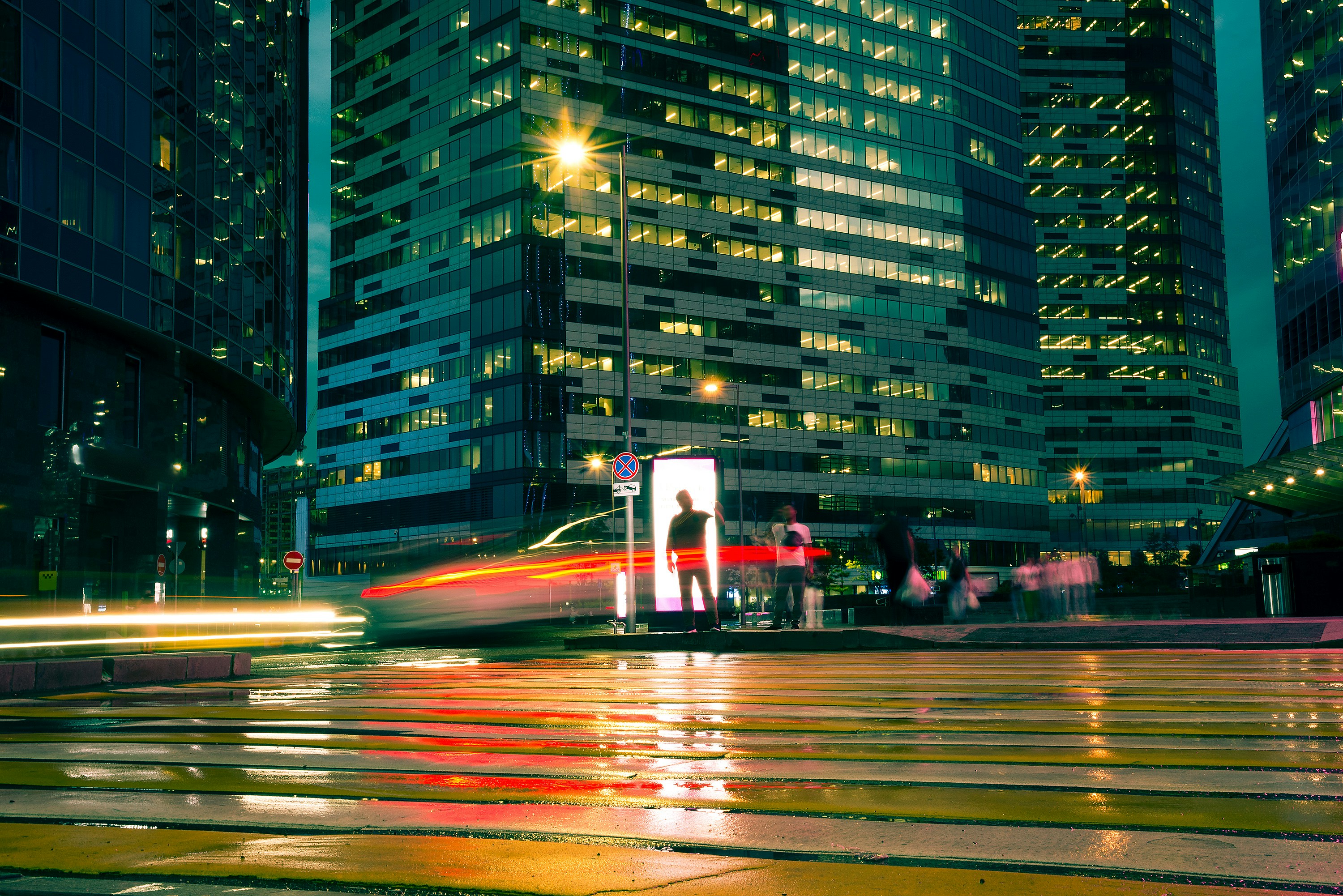 City street at night with light trails and illuminated buildings.