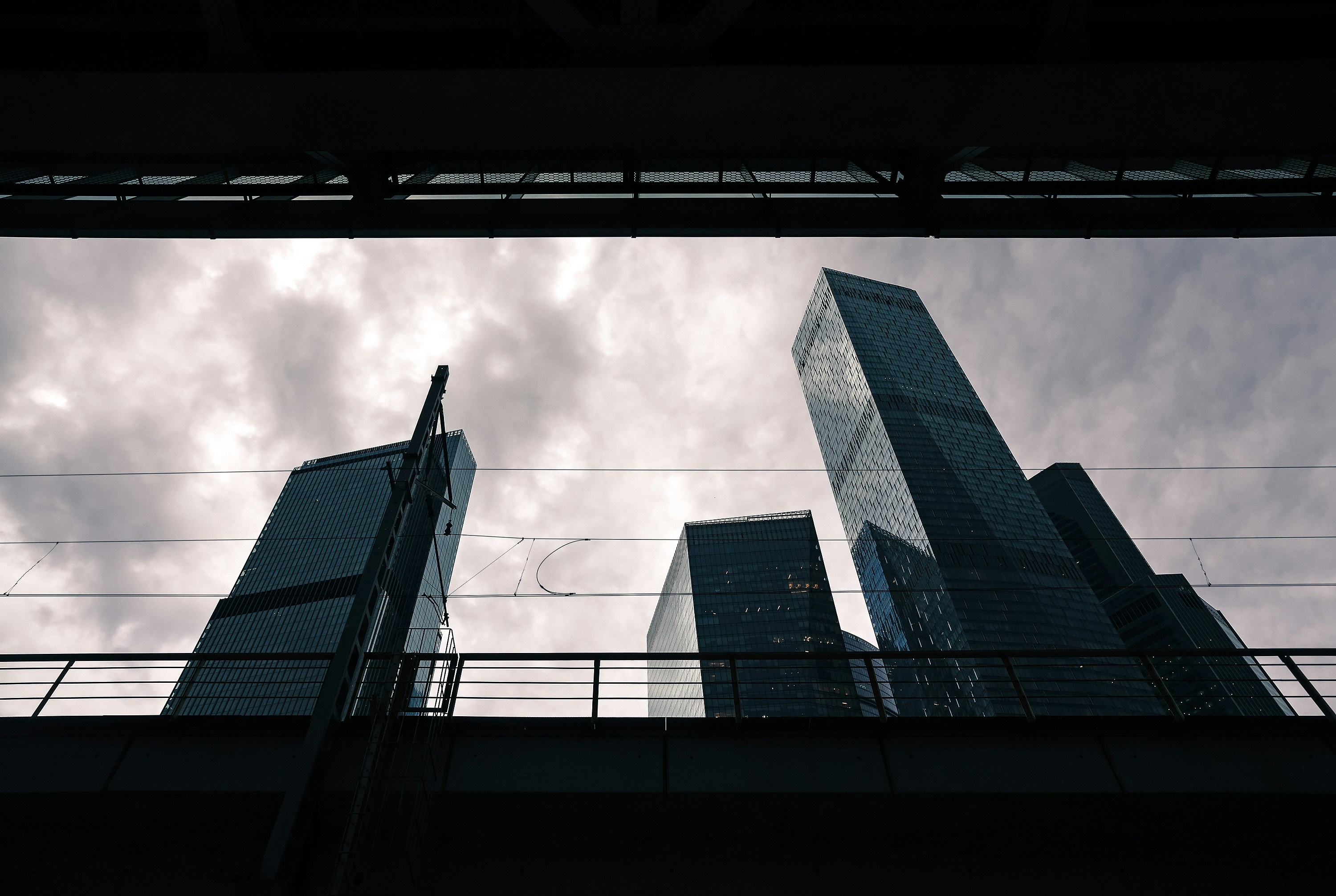 Tall modern skyscrapers against a cloudy sky from below.