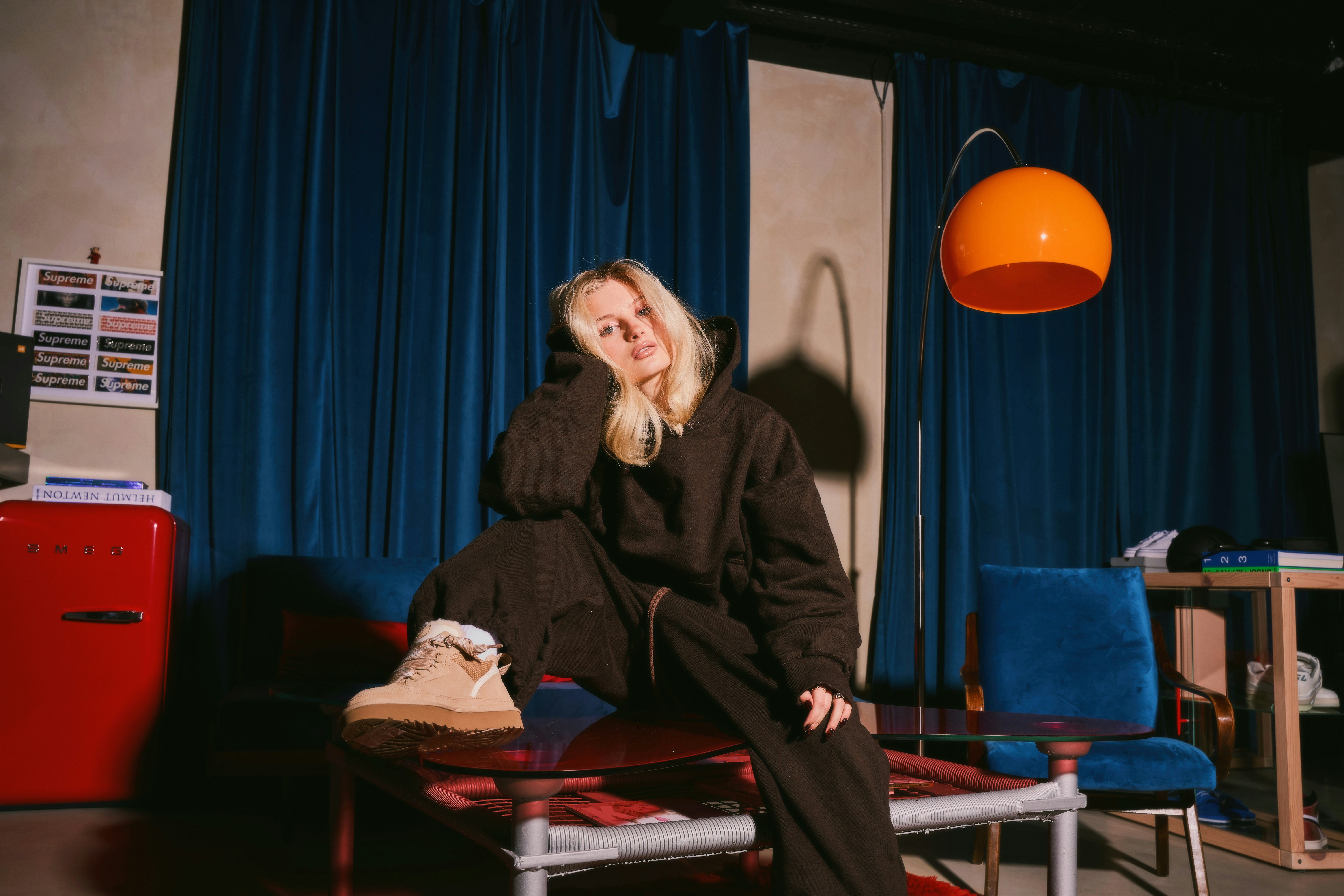 Young woman in brown loungewear sitting in a quirky room.