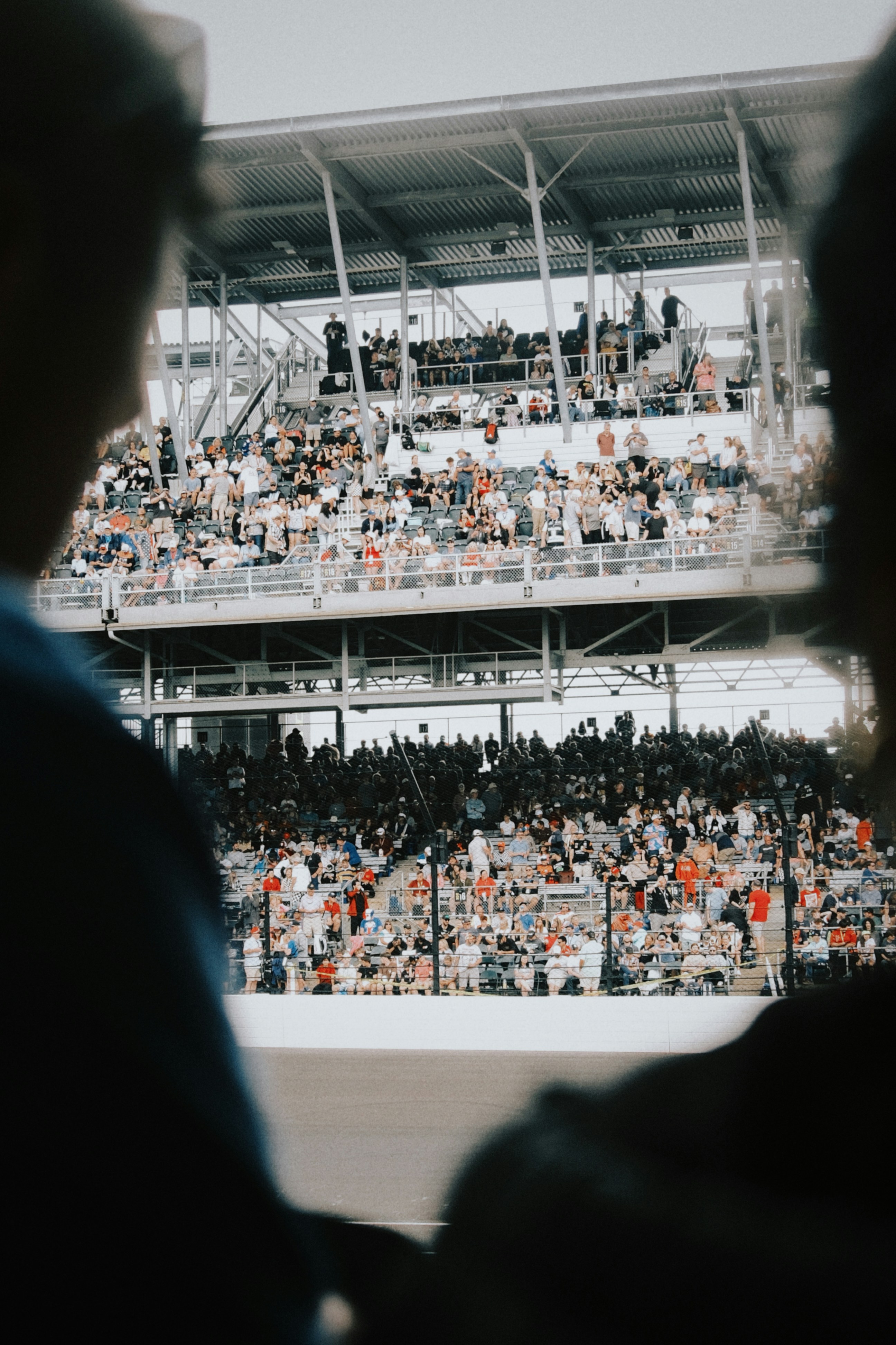 Two people watch a crowded stadium filled with spectators.