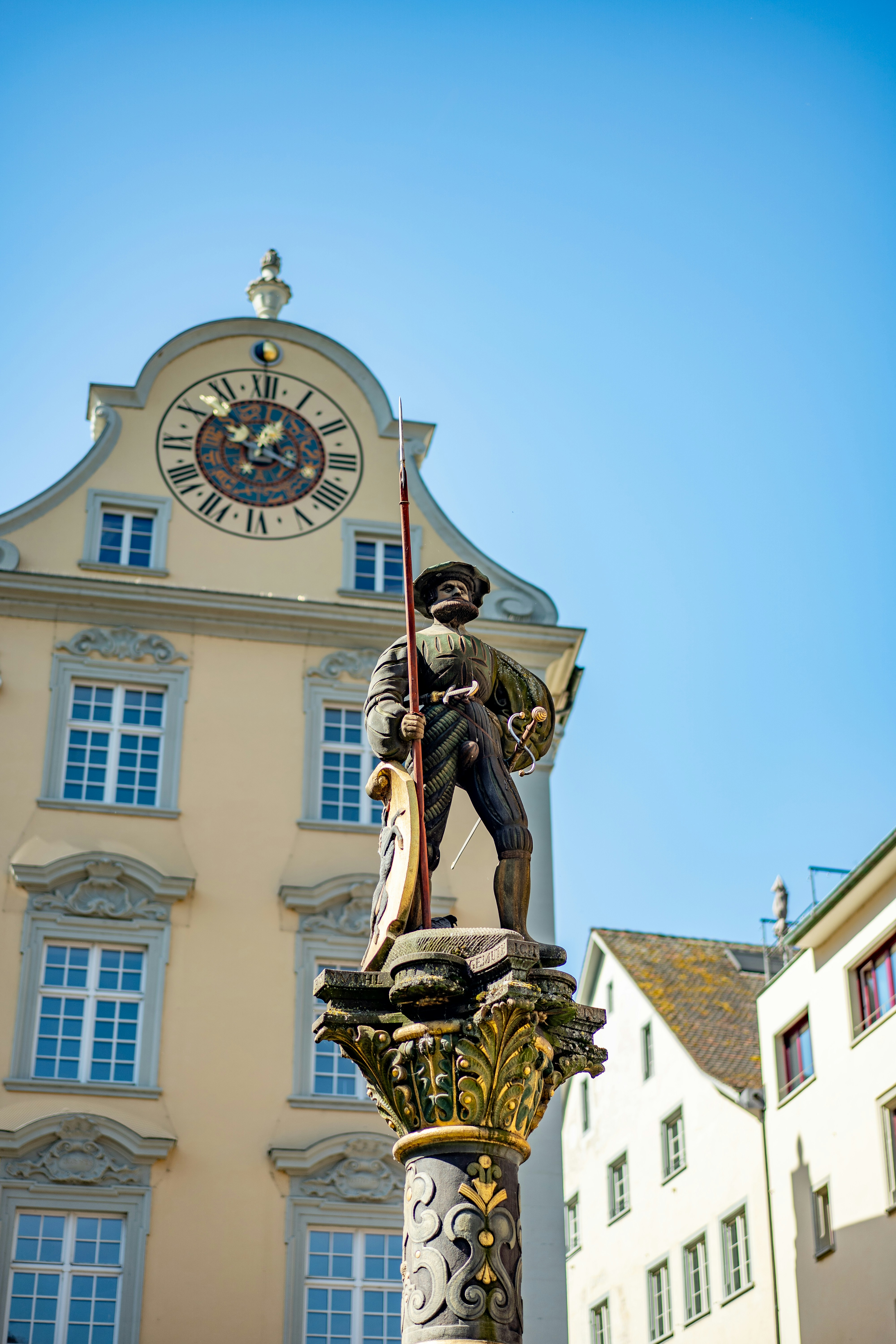 Statue historique de guerrier contre un bâtiment avec une grande horloge.