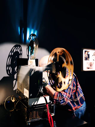 A person operates a vintage film projector with golden reels.