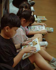 Young children quietly read comic books on the floor.