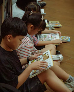 Young children quietly read comic books on the floor