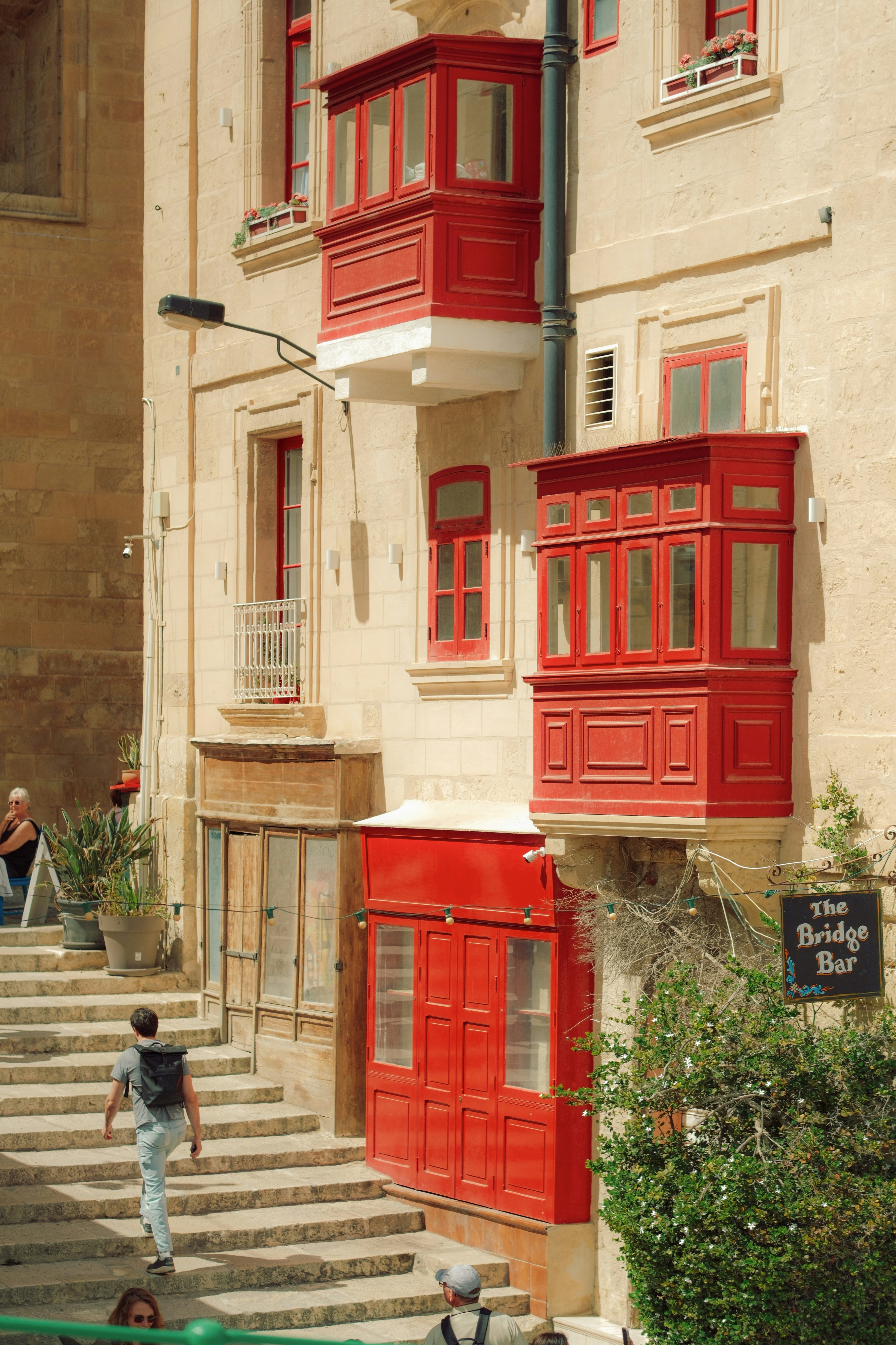 Man walks up stairs past building with vibrant red balconies