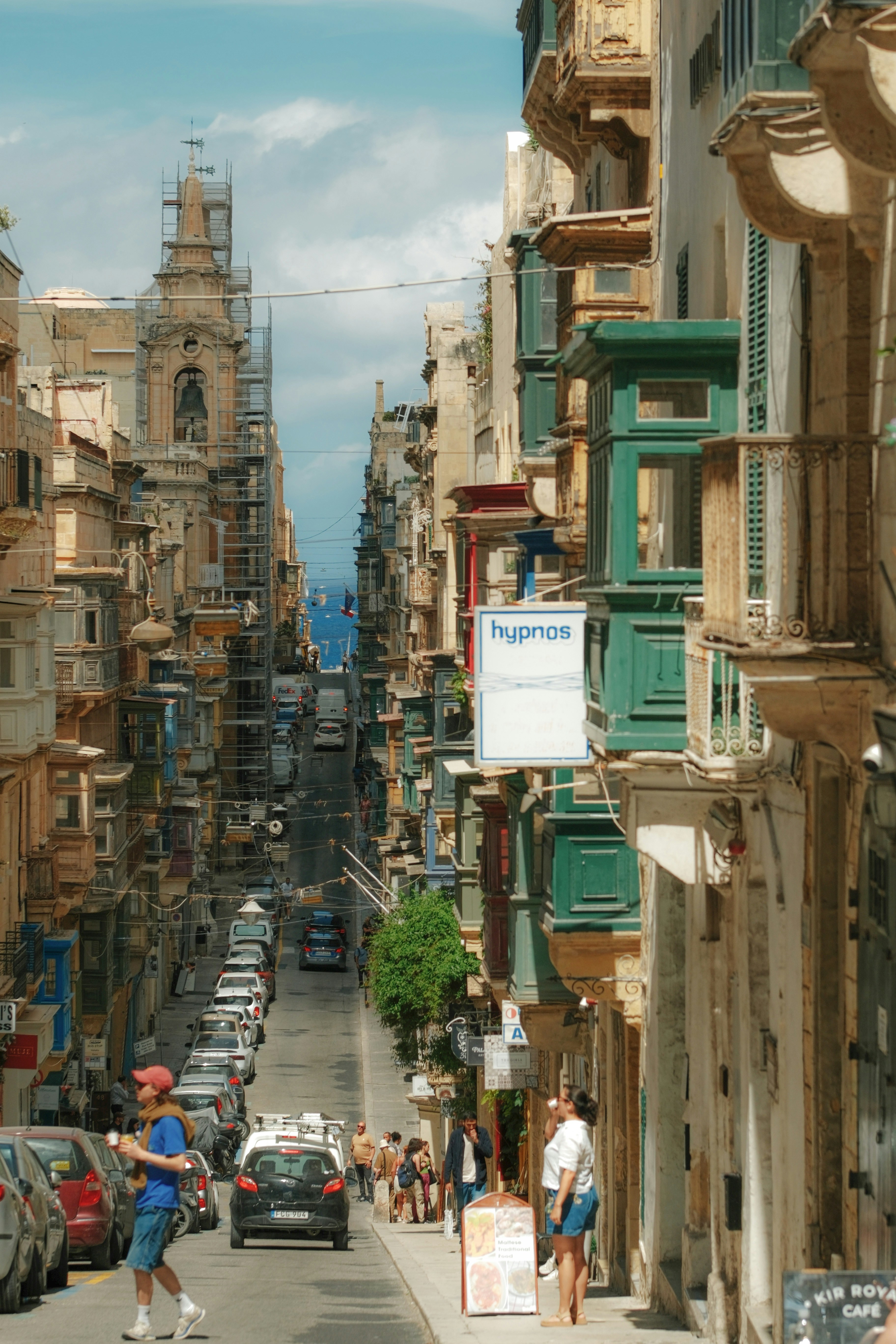 Historic street scene with traditional balconies, cars, and people