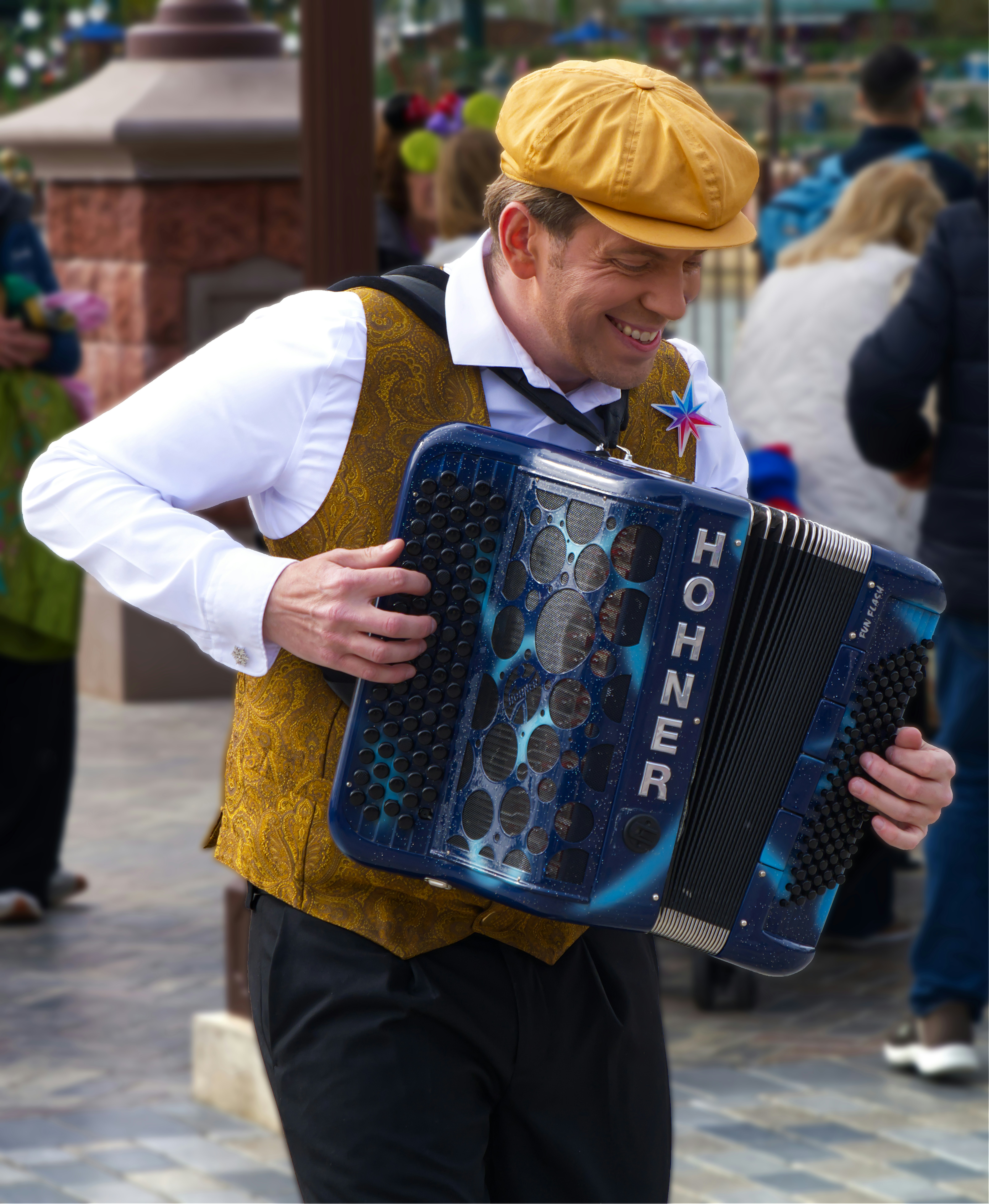 Un hombre sonriente toca un acordeón azul hohner al aire libre.