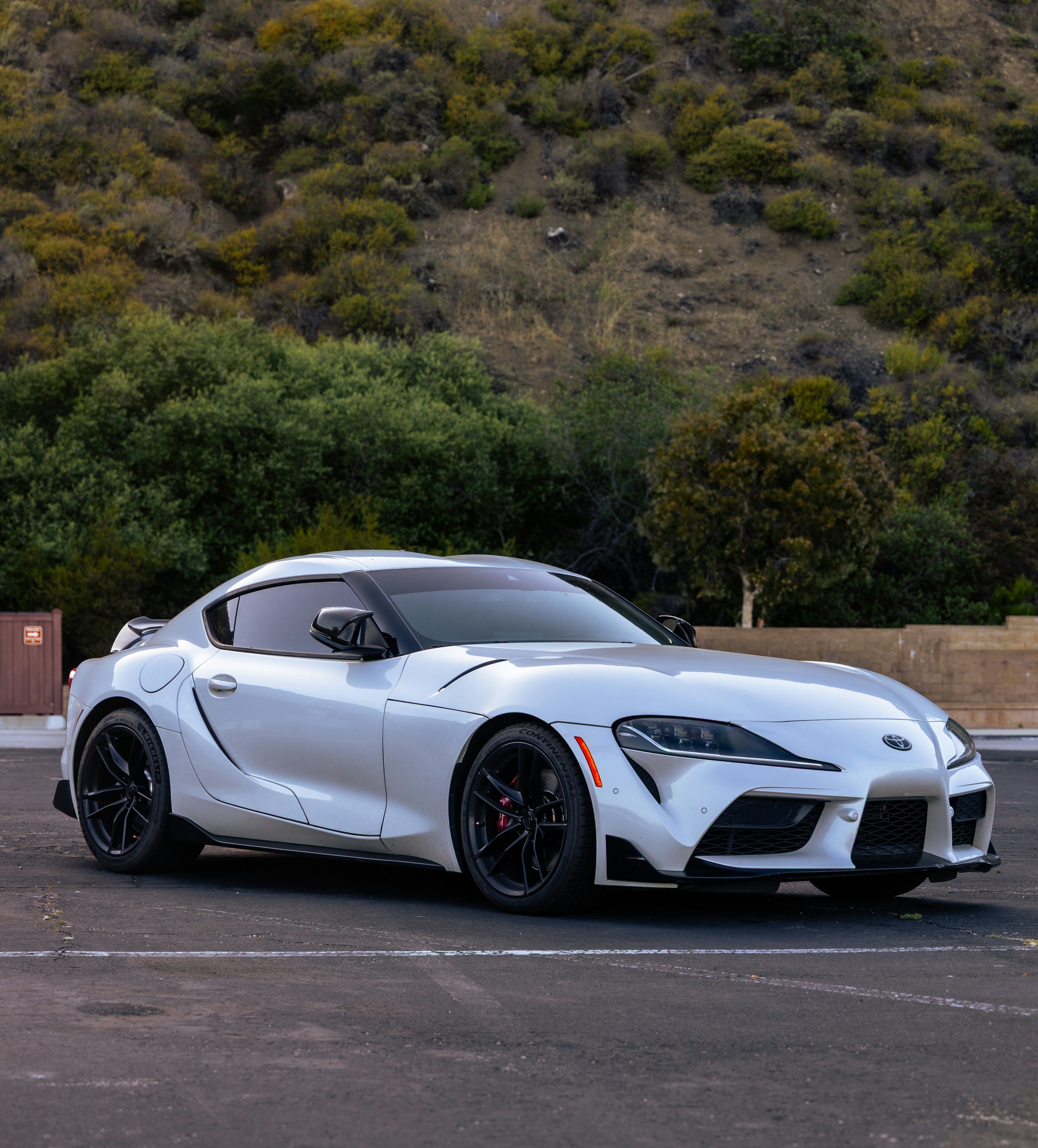Sebuah mobil sport toyota supra putih diparkir di luar ruangan dengan perbukitan.